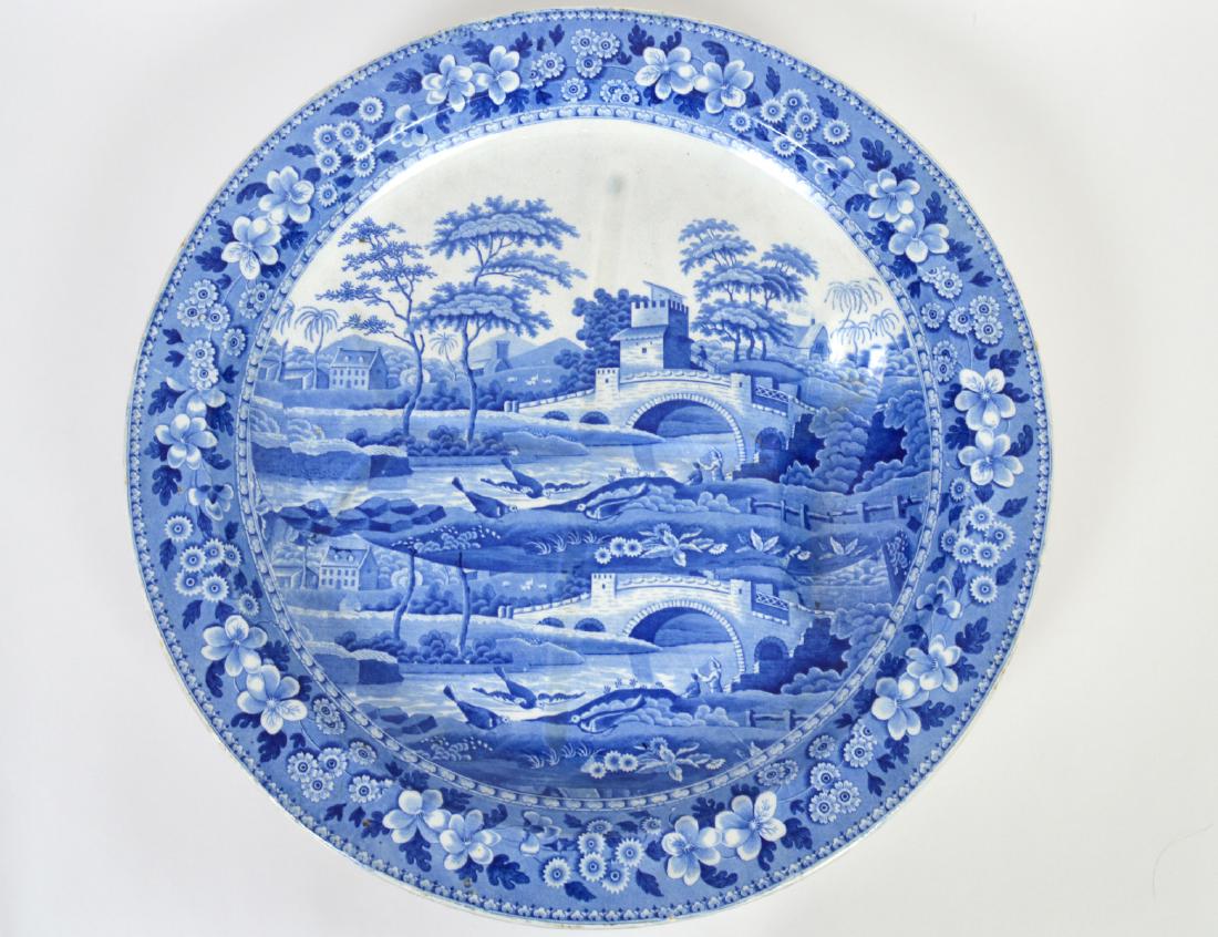 RARE LARGE STAFFORDSHIRE CIRCULAR MEAT PLATTER: Early 19th Century. Possibly Spode. Transfer decorated in blue to depict an English village. Diameter 21”. (Cond: good)