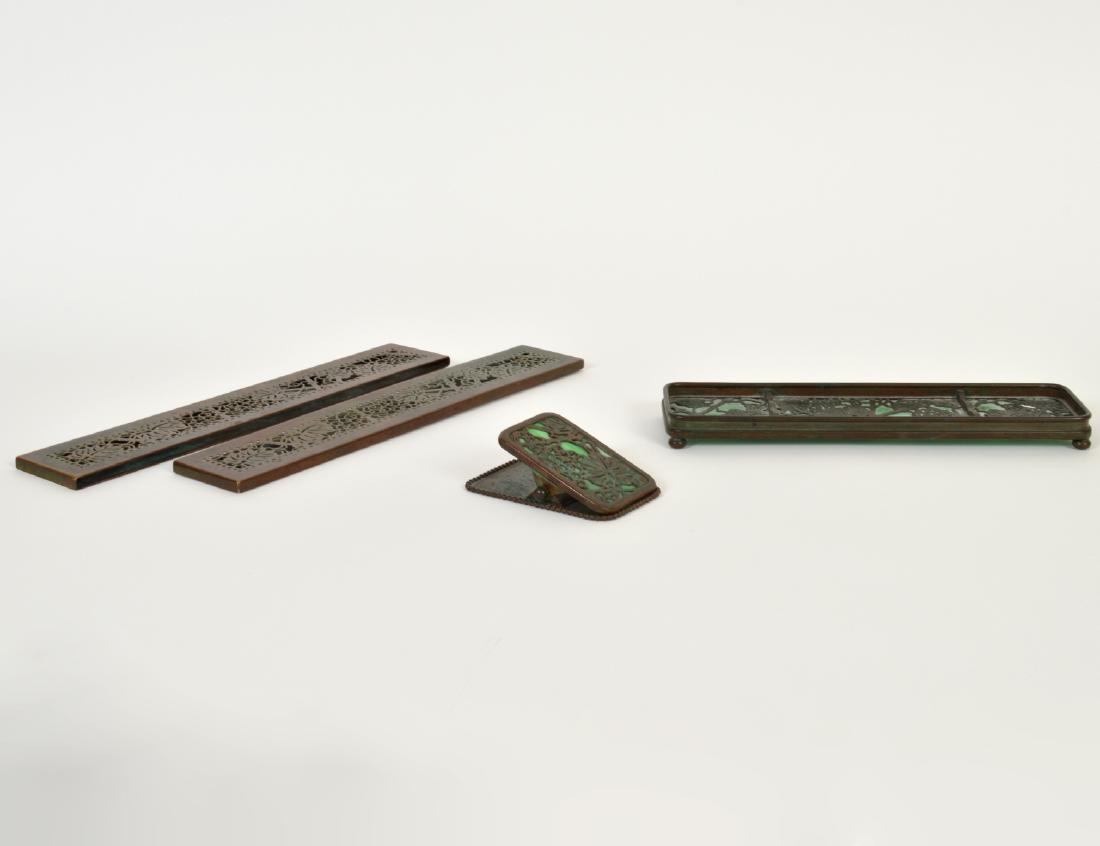 TIFFANY STUDIOS PEN TRAY, PAPER CLIP & BLOTTER END: Circa 1900. Stamped Tiffany Studios, New York, numbered 1004, 971. 998, respectively. In the “Grapevine” pattern, with green slag glass. Width of pen tray and blotter ends 9 ½”,