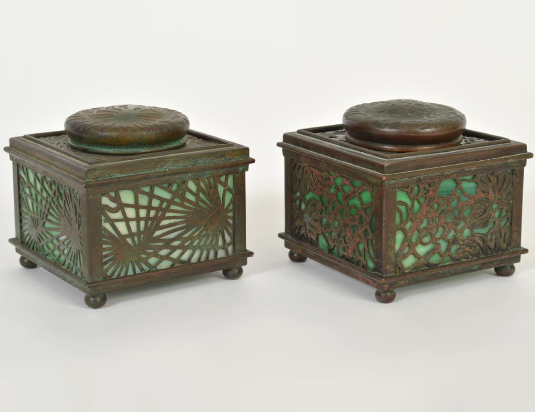 TWO TIFFANY STUDIOS PATINATED BRONZE INKWELLS: Circa 1900. Stamped Tiffany Studios, New York numbered 845. With green slag glass. Height 3”. Width 3” square. (Cond: One lacks glass inset and its surface surrounding the lid with damages