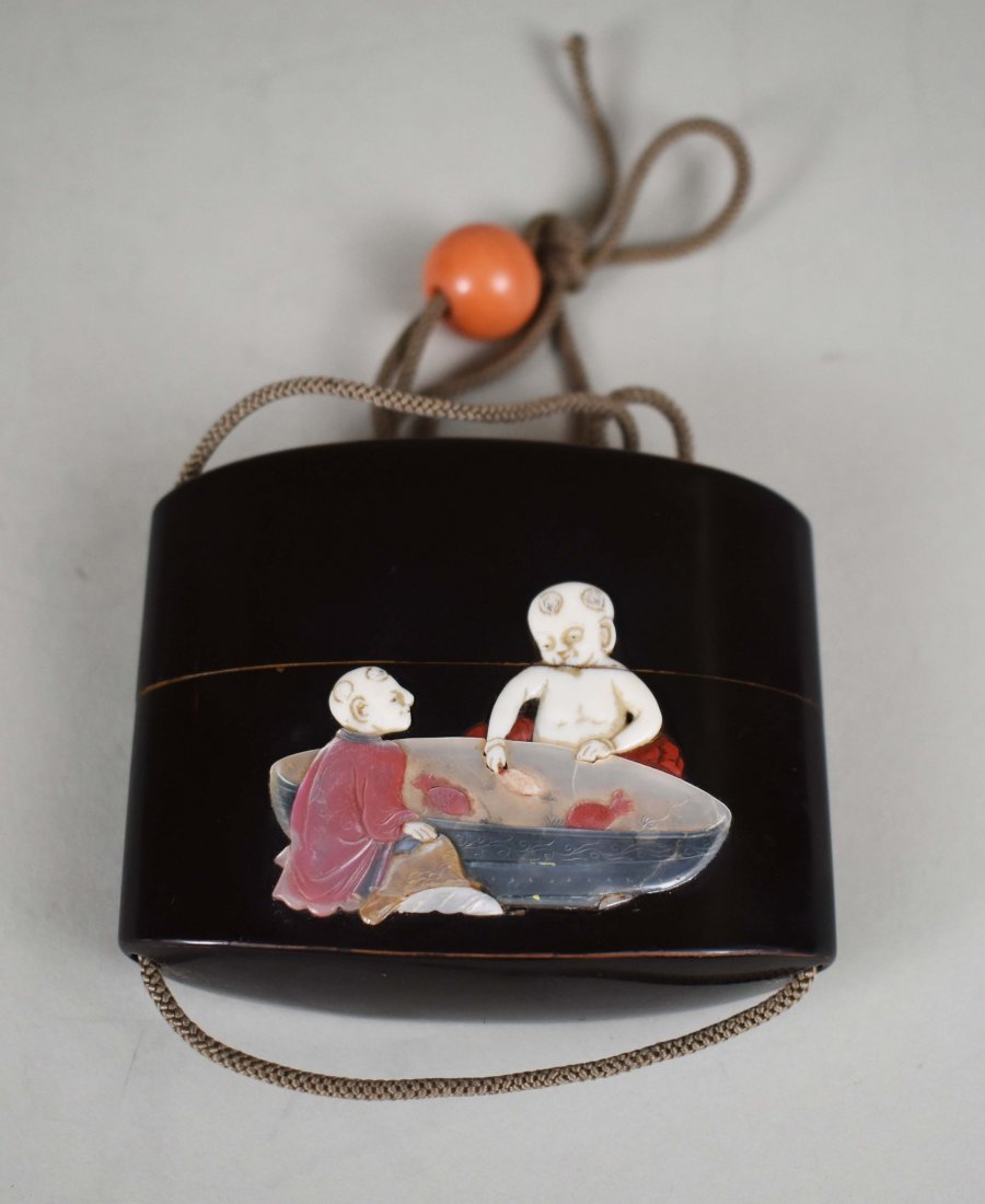 JAPANESE BLACK LACQUER INRO: Early 20th Century. The exterior mounted with abalone and other material to depict boys at play, with a red lacquer interior. Height 2.5 in. (Cond: good)