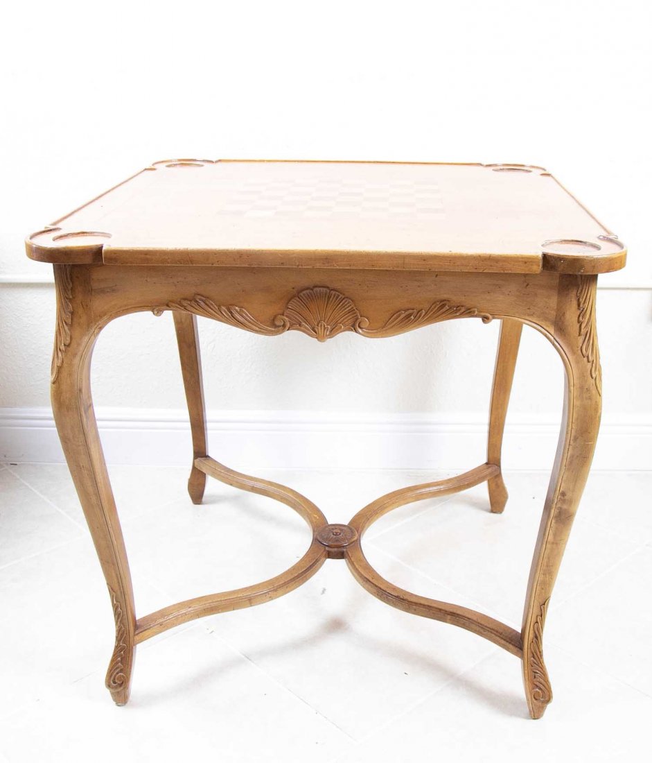 ITALIAN ROCOCO STYLE CARVED WOOD GAMES TABLE: The square top with corner recesses and an inlaid chessboard, above a carved frieze, on cabriole legs joined by an X-form stretcher. Height 29 in. Width square 29 in. (Cond: has veneer loss to top)