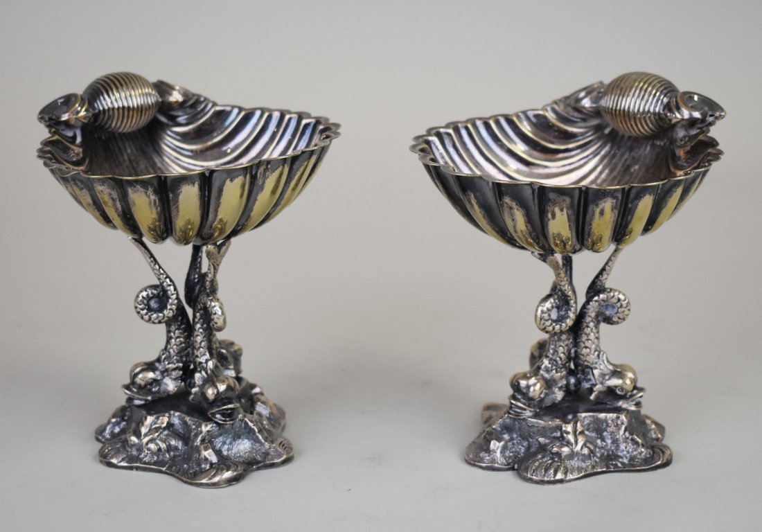 PAIR OF BAROQUE STYLE SILVER PLATE MASTER SALTS: Probably Italian. Early 20th Century. Each cast as three dolphins supporting a shell, atop rockwork. Height 5.75 in. Width 4.5 in. (Cond: good)
