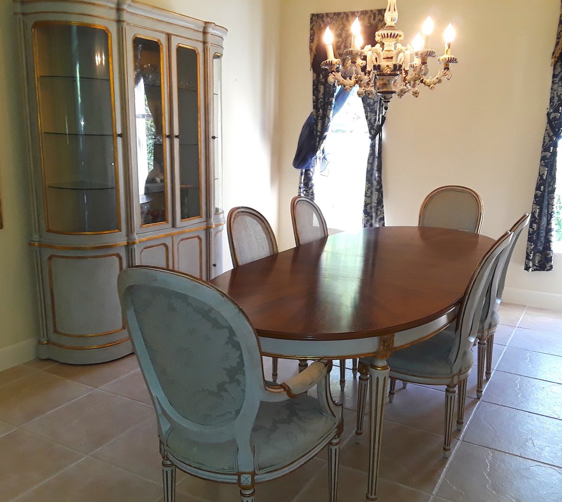 LOUIS XVI STYLE NEO-CLASSICAL DINING RM FURNITURE: 20th Century. Comprising: a dining table with a mahogany veneered top, with a painted and gilt frieze, on circular tapered fluted legs. With three leaves, two parcel gilt and painted armchairs, four c