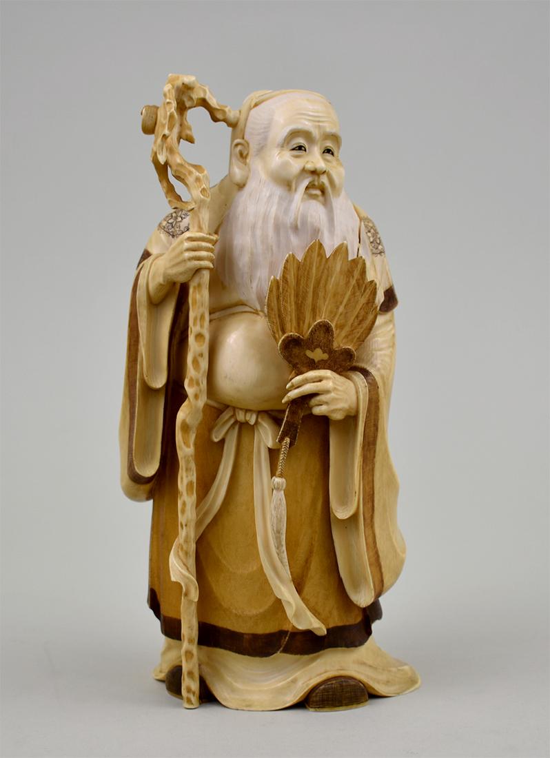 JAPANESE FIGURE OF A BEARDED SCHOLAR: Late 19th Century, Meiji Period. Signed on the underside. The elderly sage with long hair, in elegant robes with staff and fan. Height 9 in. Width 4.5 in. (Cond: crack at left shoulder running down le
