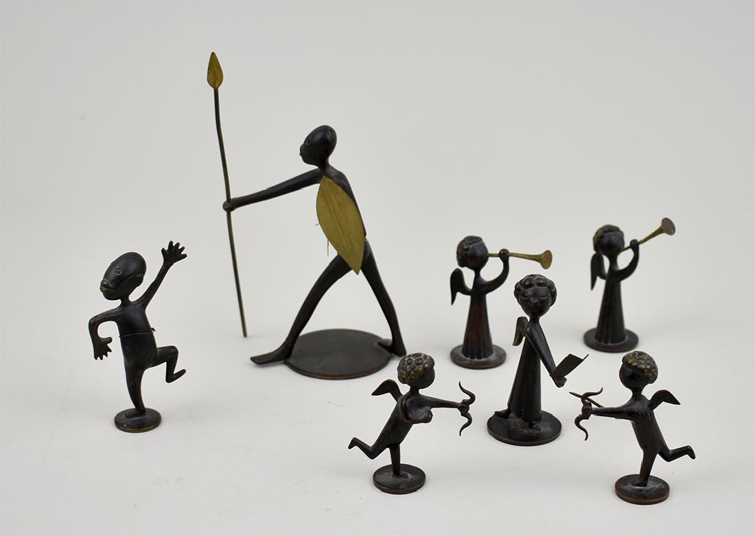 SEVEN HAGENAUER PATINATED BRONZE MINIATURE FIGURES: Austrian. Circa 1920. Each marked Hagenauer Wien, Hand Made, and with symbols on the underside. Comprising: an African warrior with shield and spear, a comical boy, two trumpet blowing angels and a pa