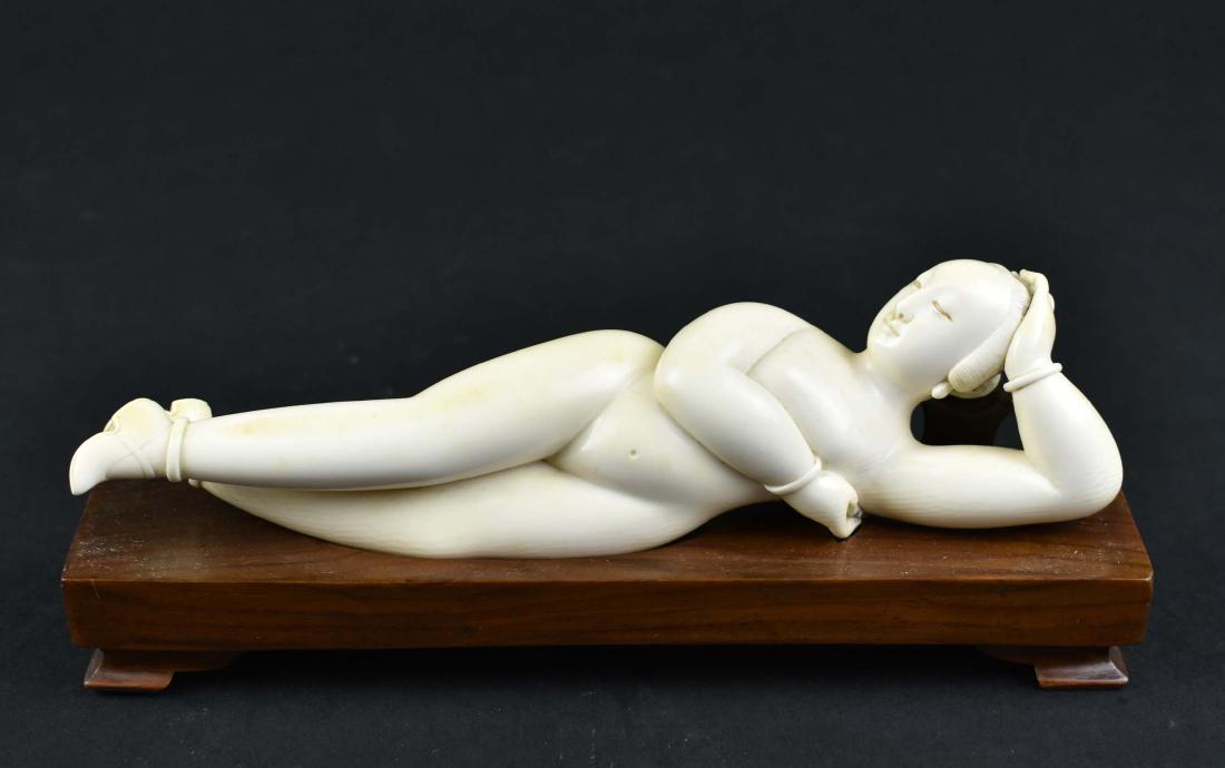 CHINESE CARVED RECLINING FEMALE NUDE: Circa 1900. The female nude wearing only her shoes lying on one side atop a wood bench. Width 8 in. (Cond: good)
