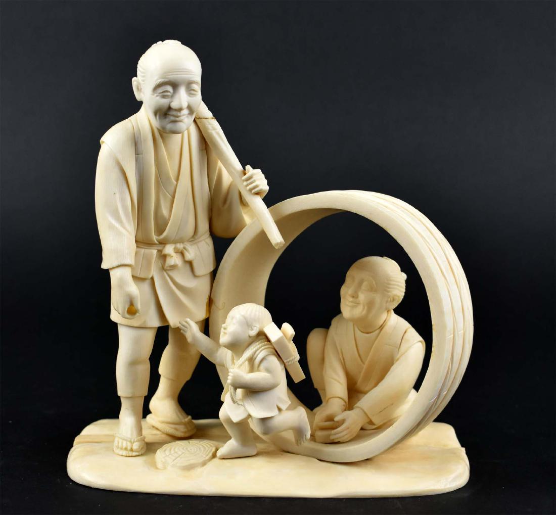 JAPANESE OKIMONO OF CARPENTER AND HIS FAMILY: Meiji Period. Signed on the underside. Depicting the carpenter returning home with a small tub slung over shoulder, the boy with a plane greets his father, his wife appears to be finished with binding