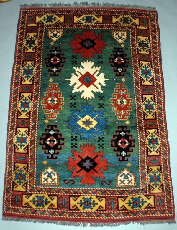 Caucasian Rug The green ground woven with seriated: Caucasian Rug The green ground woven with seriated medallions and latch hooks, enclosed by a paneled primary border. Measures 5'10" x 3' 11". AGOPB will not pack or ship items; please contact the gall