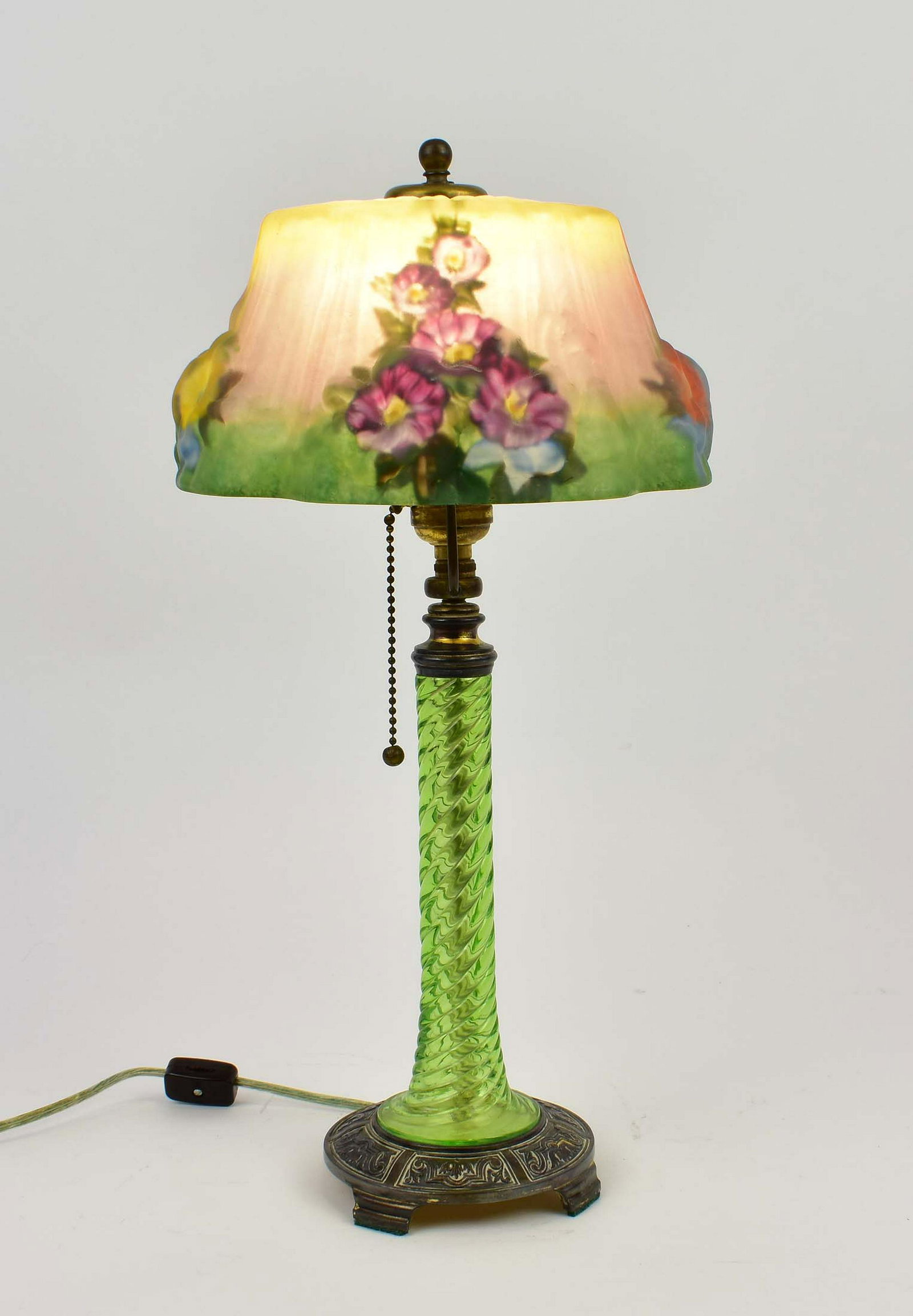 PAIRPOINT PUFFY REVERSE PAINTED HOLLYHOCK TABLE LAMP: 1900-1920. The shade marked The Pairpoint Corp. in silver, the base with P in a diamond, numbered D 3083. The circular shaped flared shade with multi colored hollyhocks on a ground of green, lavender 