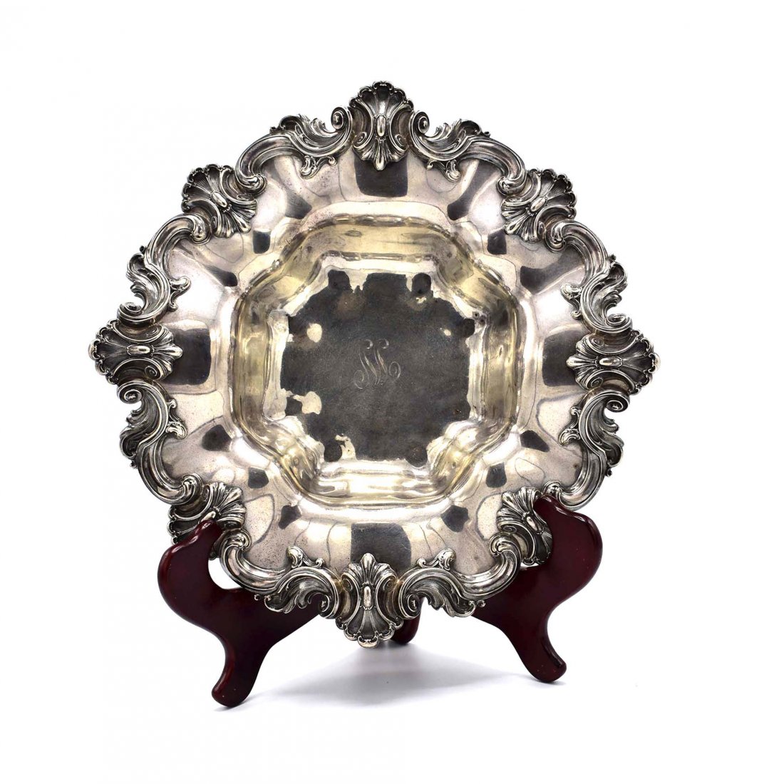 AMERICAN ROCOCO STYLE STERLING SILVER FRUIT BOWL: Post 1871. R Wallace & Sons, marked sterling, initialed and with a stag's head, numbered 1220. The shaped circular bowl with a border cast with scrolls and feathered cabochons, the center recess monog