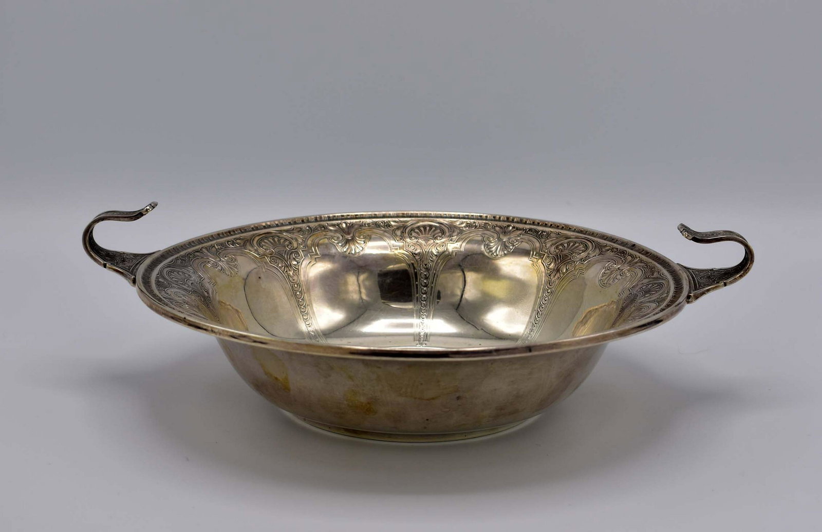 AMERICAN STERLING SILVER CIRCULAR BOWL: Circa 1900. Marked G S Co. Sterling. In a Renaissance style, with shaped rim and two curved handles, chased overall with stylized shells within scrolled arches with divided by overlapping graduating d
