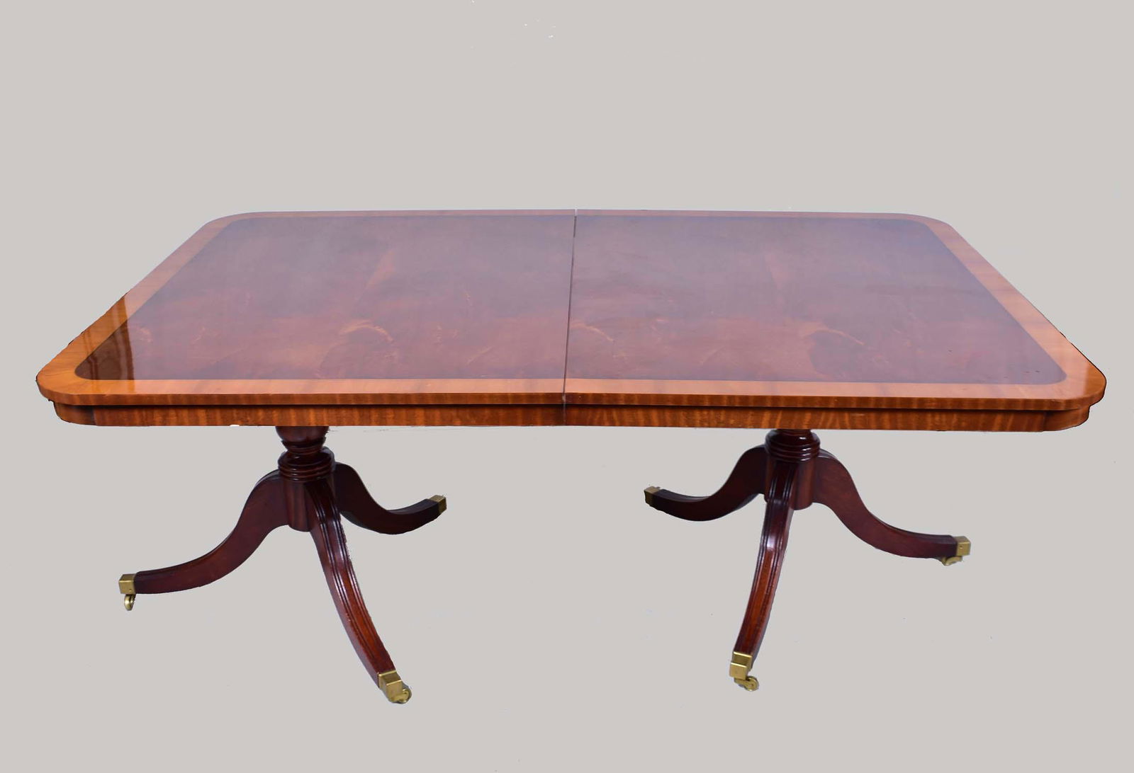 ENGLISH INLAID MAHOGANY TWO-PEDESTAL DINING TABLE: 20th Century. In a George III style,two baluster turned pedestals, on four down-swept legs, ending in brass caps with casters, with one leaf. 32 in. high. 72 in wide. 47.5 in. depth Overall measures w