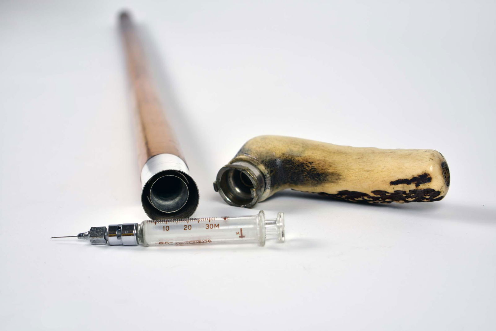 ANTIQUE GADGET CANE WITH DOCTORS' SYRINGE: 19th Century. Probably English. Carved antler handle opens to reveal a compartment with a doctor's glass syringe. Length 32 in. (Cond: good, normal wear for age and use)