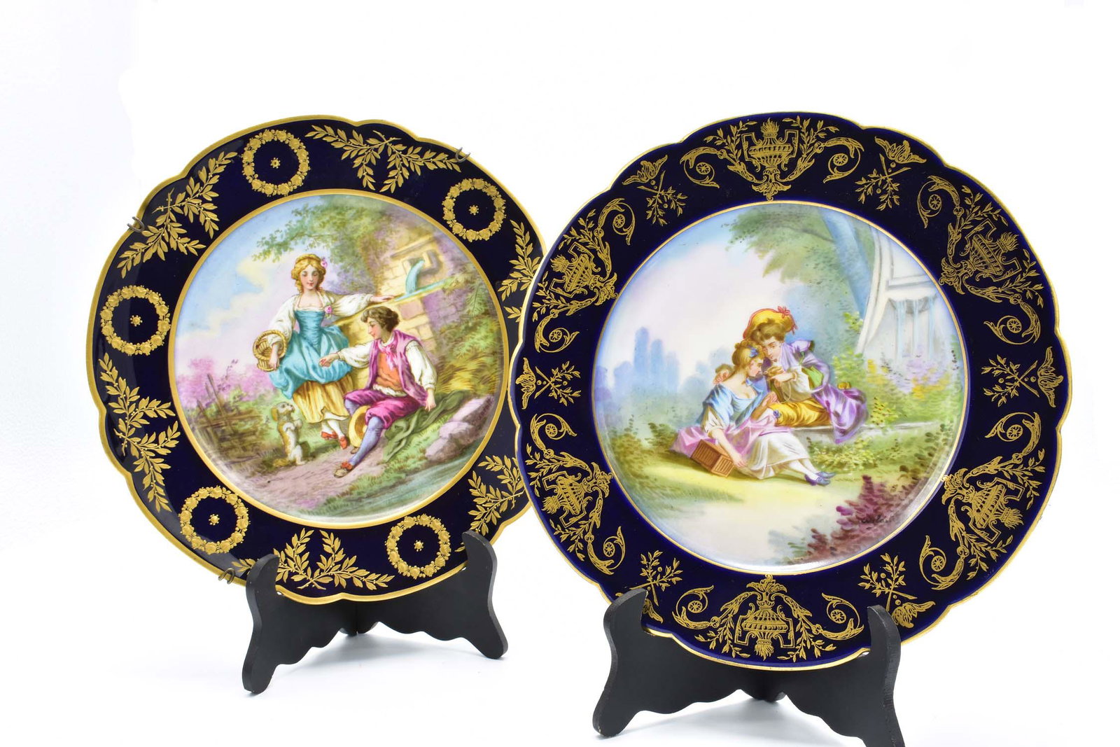 TWO SEVRES PAINTED PORCELAIN CABINET PLATES: 20th Century. The underside of one marked with an S within crossed swords in blue, the other with collection marks. Each shaped circular plate decorated with a pair of lovers in pastoral landscapes, w
