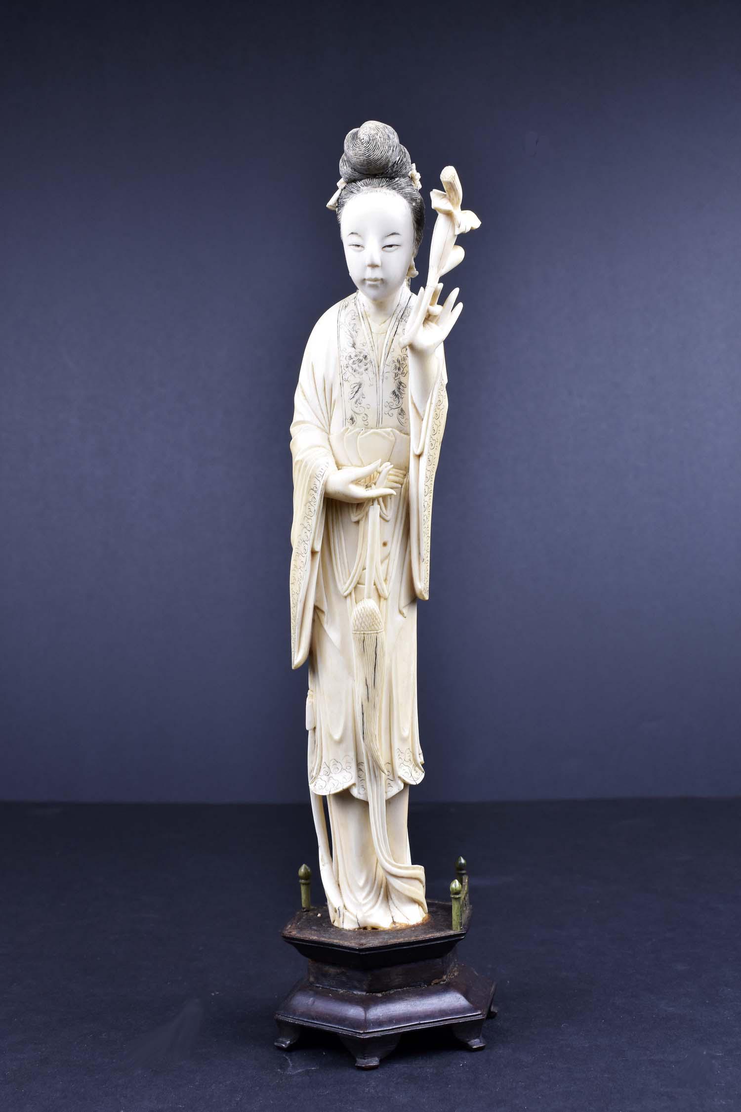 CHINESE CARVED FIGURE OF A MEIREN: Elegantly dressed, her hair neatly coiffed, holding a floral stem and a wisp. Height 10 in. (Cond: good)