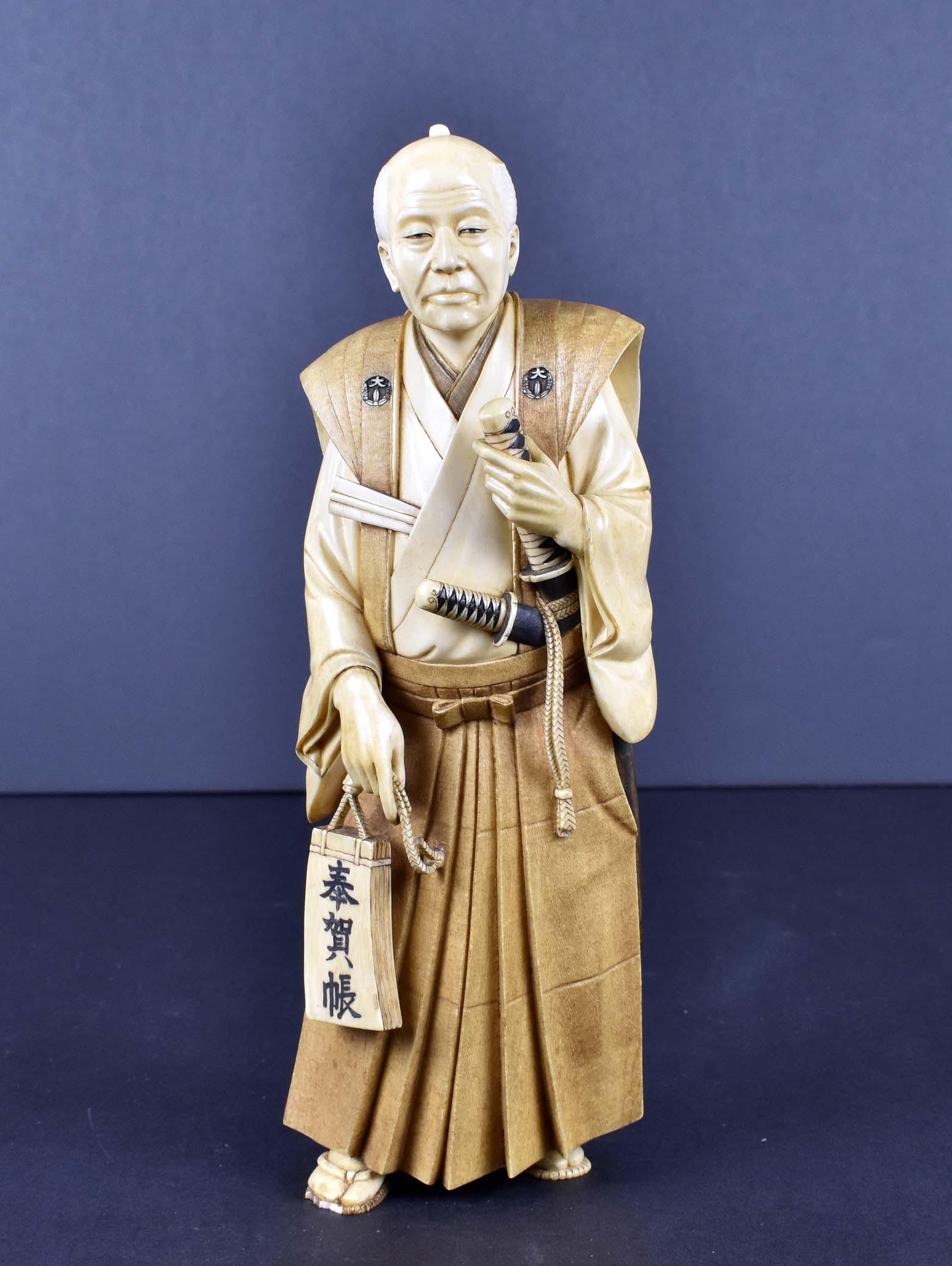 JAPANESE OKIMONO OF A SAMURAI: Meiji Period. The underside with a artistâ€™s monogram. The handsome elderly man, his hair well coiffed into a long knot, wearing an inside and outside pleated robe, the outside robe bears rounde