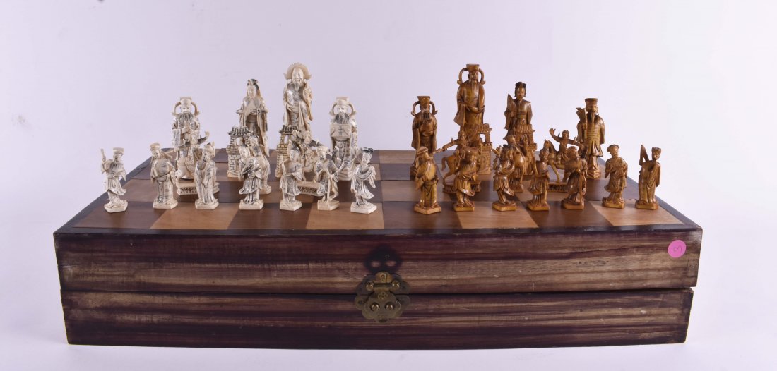 CHINESE CARVED BONE CHESS SET: 20th Century. The figures well carved to depict on each side Chinese Nobles and Court Officials, one side stained brown, the other white, in a silk lined fitted folding inlaid wood case that serves as