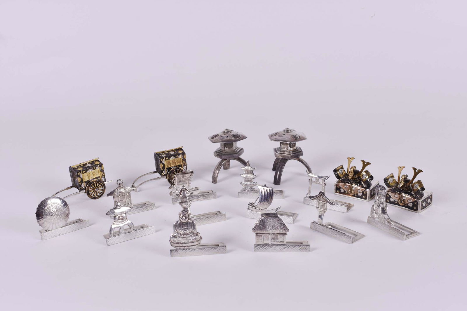 THREE PAIRS OF JAPANESE SILVER & GILT SALT/PEPPER: Together with Twelve Silver Place Card Holders. All marked. Comprising: a pair of lanterns, a pair of carriages and a pair of Samurai helmets on tablets, the placeholders with various motifs. (18 pcs)