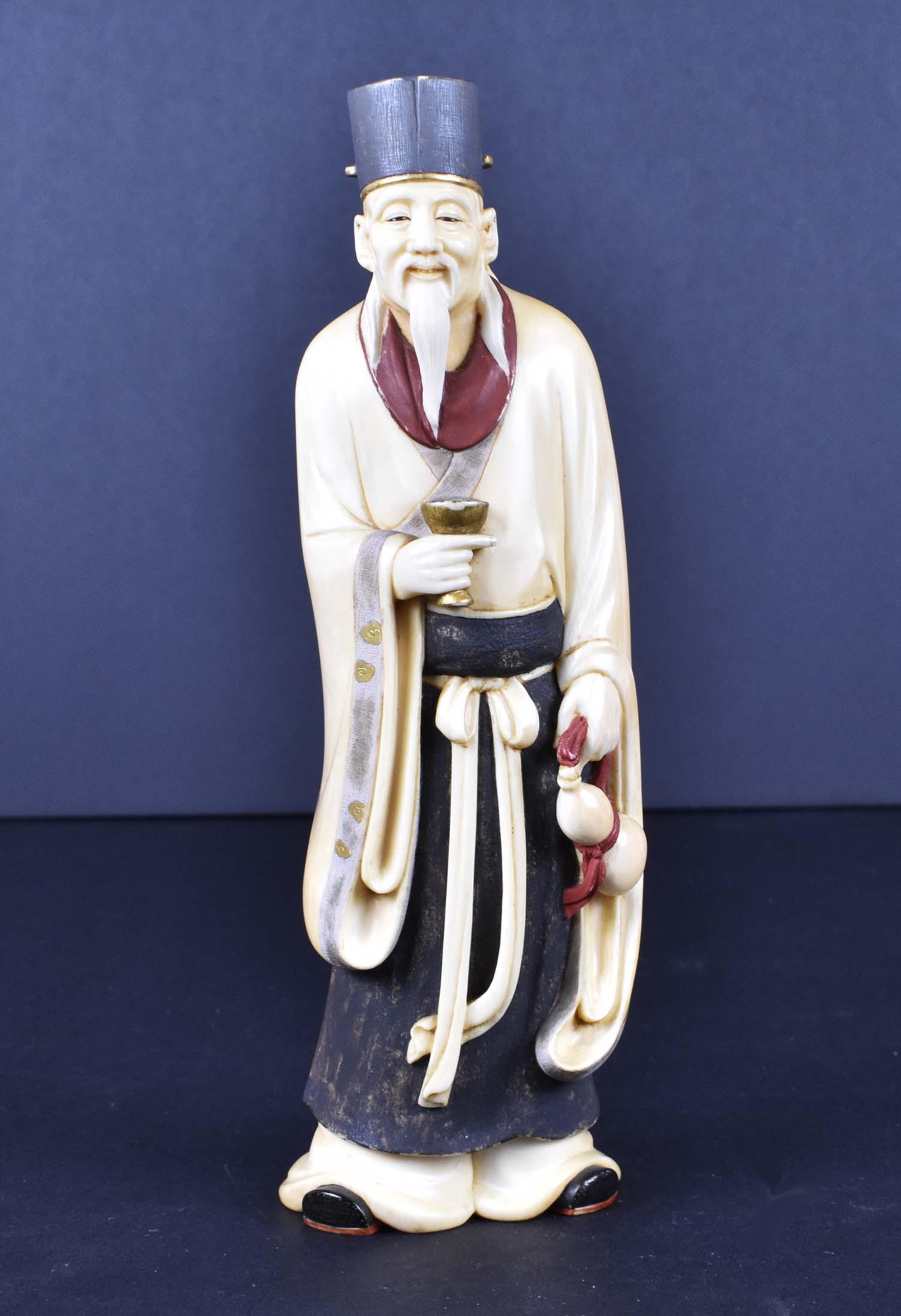 JAPANESE TEA AND RED STAINED OKIMONO OF A MYSTIC: Meiji Period. Signed Seiko on a red inset tablet. The bearded gentleman in a long robe, gathered at his waist with a tied sachet, he holds a gilt cup and a water-filled gourd. Height 8 in. (Cond: good