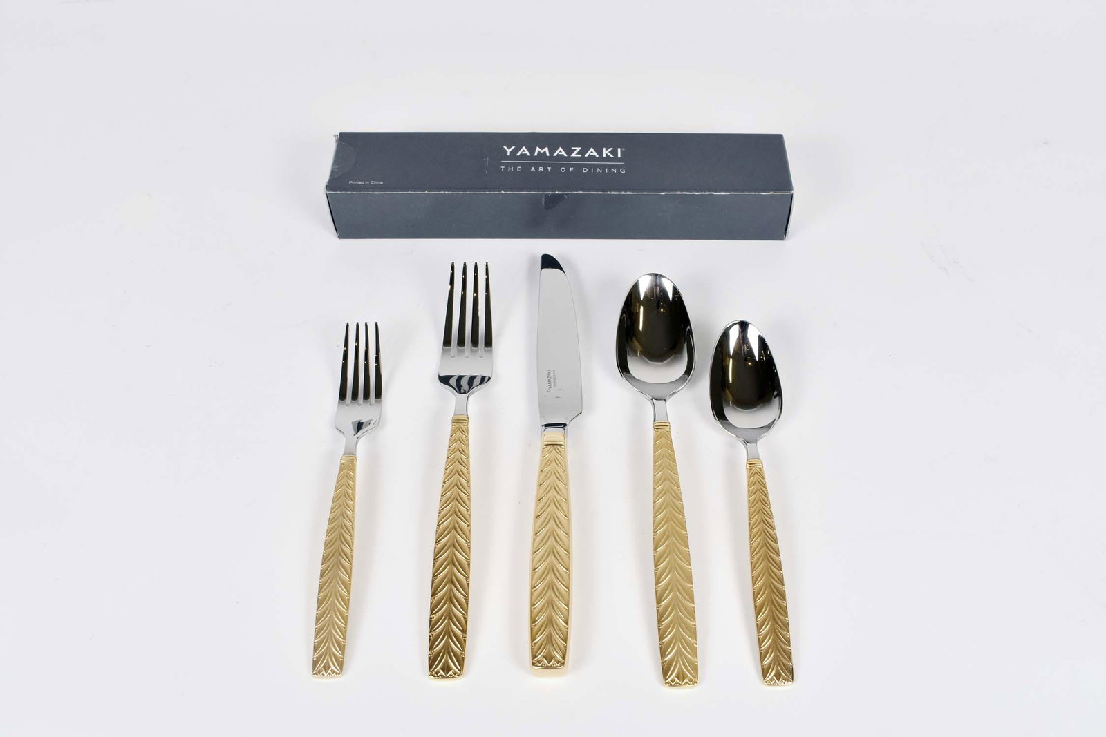 YAMAZAKI GOLD PLATED FLATWARE SERVICE FOR FOURTEEN: Japan. In the Feather Gold Pattern. The handles cast as two vertical rows of feathers. Comprising a knife, a dinner fork, salad fork, tablespoon and a teaspoon, the handles plated in gold. (70 pieces)