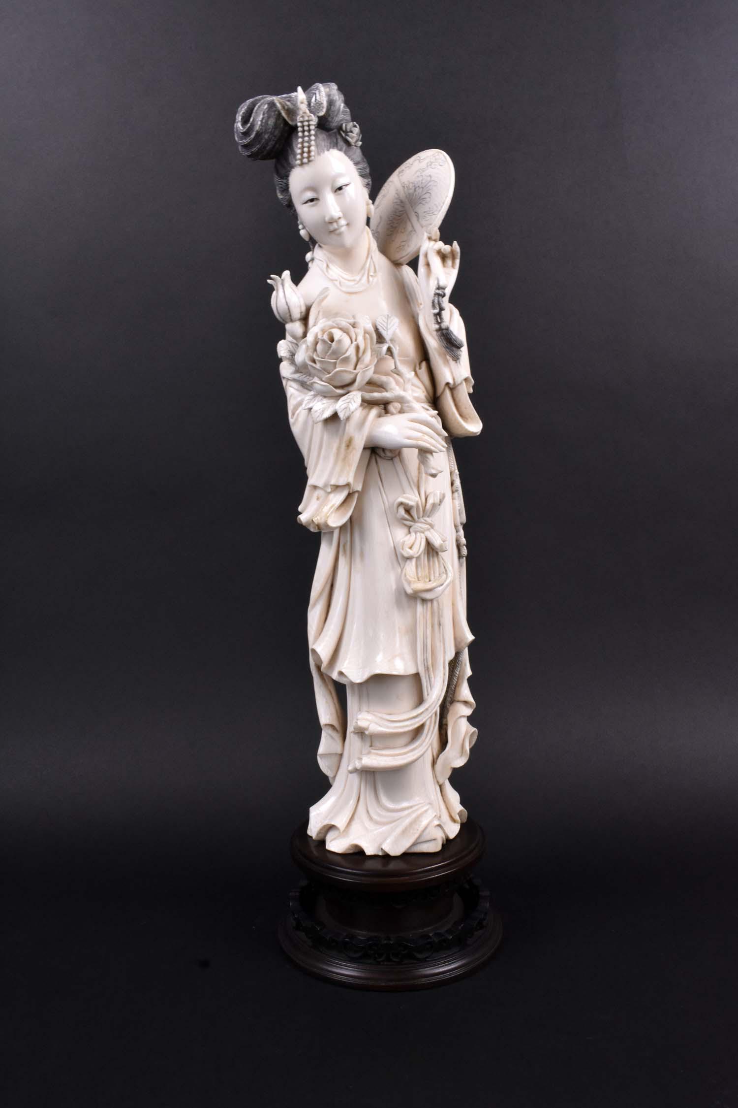 FINE CHINESE CARVED FIGURE OF A MERIN: The elegant lady with elaborate coifed hair, wearing layered robes, holding a chrysanthemum stem and a fan. Height 15.5 in., overall 18.5 in. (Cond: good)