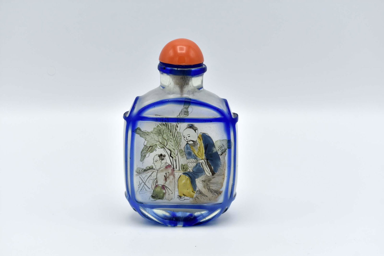 CHINESE CUT BLUE OVER CLEAR GLASS SNUFF BOTTLE: The squared oval body internally painted with a scholar and his pupil, the cap lacks spoon. Height 3.5 in. Width 2 in. (Cond: lacking spoon, otherwise good)