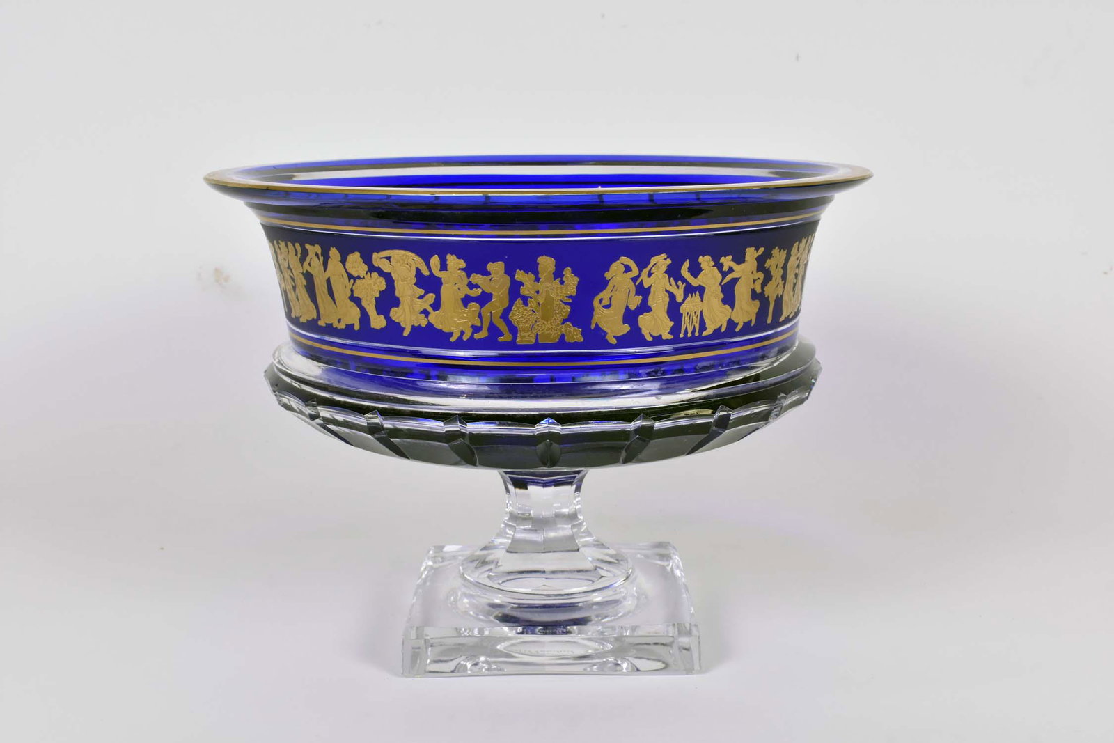 VAL ST. LAMBERT CUT GLASS BORODINE CENTER BOWL: Signed in script on the underside. Referred to as Danse de Flore. The circular bowl on a fluted stem on a square base, decorated in cobalt cut to clear, with a band of gilt Classical figures. Height 9