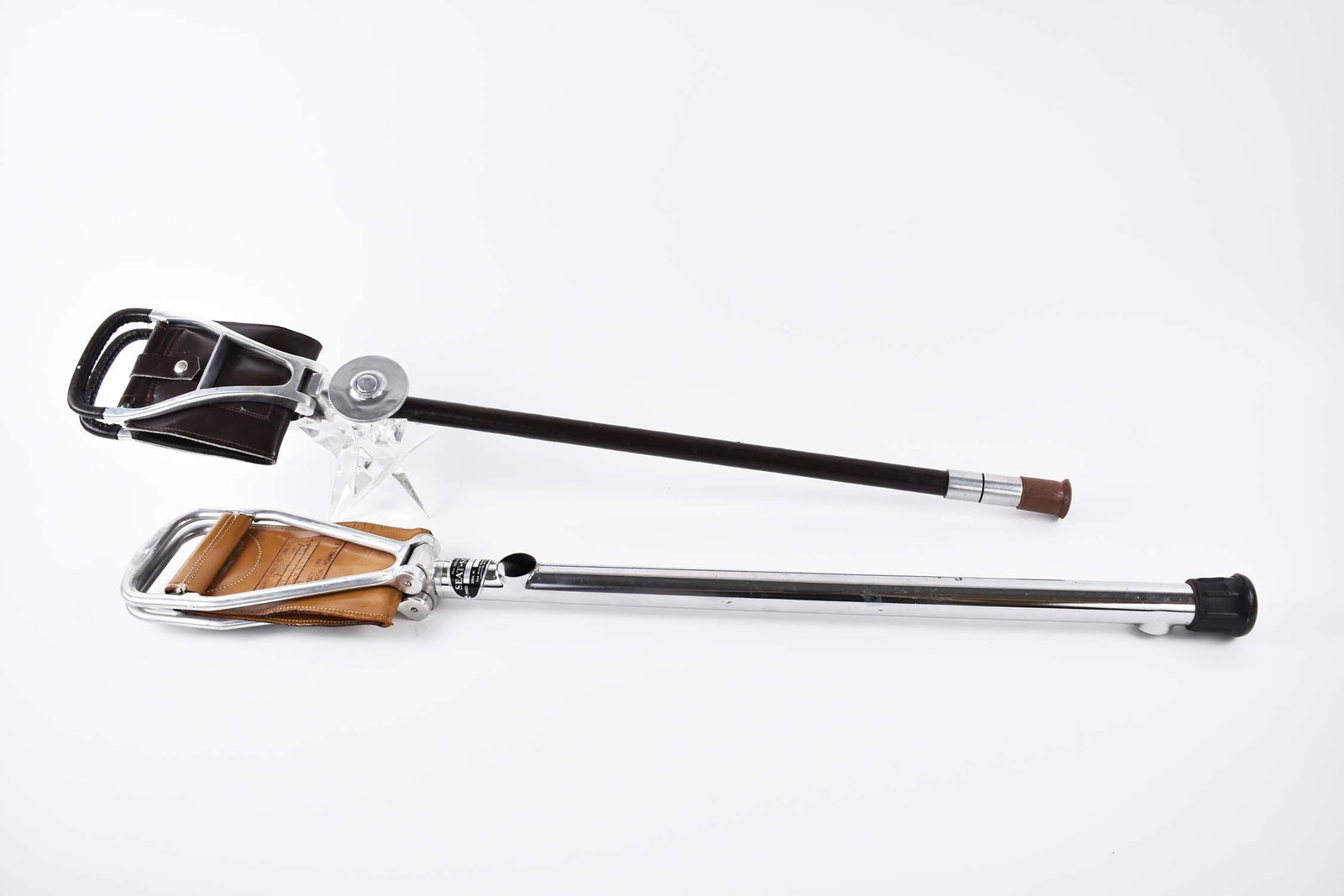 TWO STAINLESS-STEEL AND LEATHER SEAT FIELD CANES: 20th Century. The first labeled Victors First Seat Scope, Serial number l852, with dual mirrors, and a hinged seat. The second, similar, unsigned, lacking mirrors and with a leather covered shaft. Len