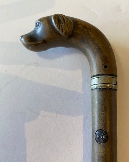 FRENCH WOOD AND STEEL DOG-HEADED CONCEALED GUN CANE: Late 19th/early 20th. The crook-shaped wood handle carved in the form of a dogs head, unscrewing from the shaft for loading, the wood shaft over a steel barrel. Length 34 in. (Cond: split to shaft, ot