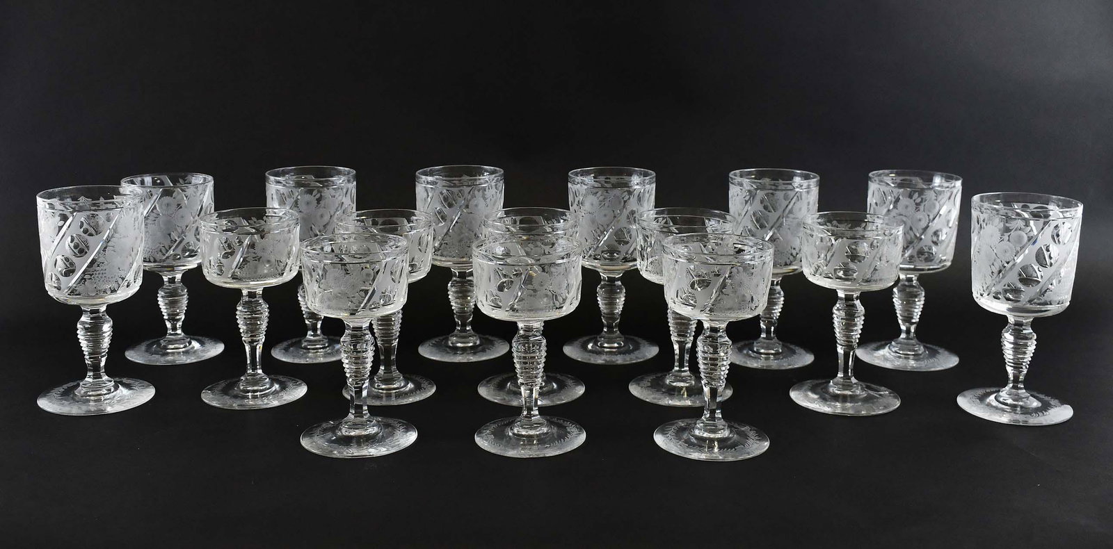 ENGLISH SIXTEEN PIECE CUT-GLASS STEMWARE SERVICE: First Half 20th century. Possibly Stevens and Williams. Comprising, eight red wines and eight white wines, in two sizes each with cylindrical bowls cut with blossoming flowers alternating with rows of
