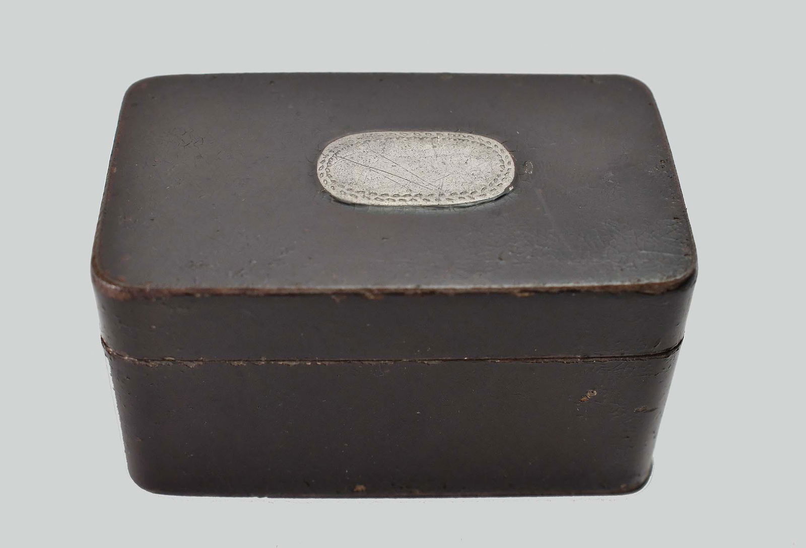 ANTIQUE ENGLISH TOLE PEINTE NUTMEG GRATER: 19th Century. The rectangular top set with an oval plaque, opening to a grating surface, the underside also with an inset plaque and hinged to reveal a catch well, painted dark brown. Measuring 1 in.