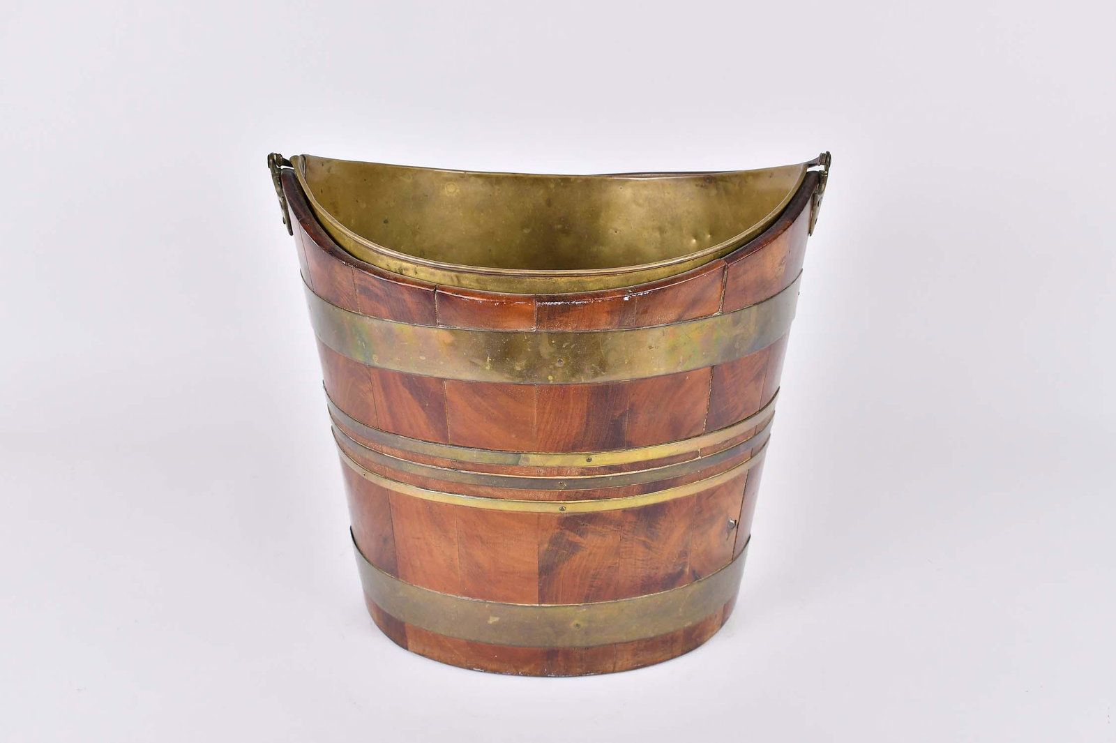 GEORGE III BRASS-BOUND MAHOGANY PEAT BUCKET: Early 19th Century. Of navette form, with a brass liner and brass loop handle. Height 13 in. Width 14.25 in. Depth 10 in. (Cond: underside repaired, otherwise ok)