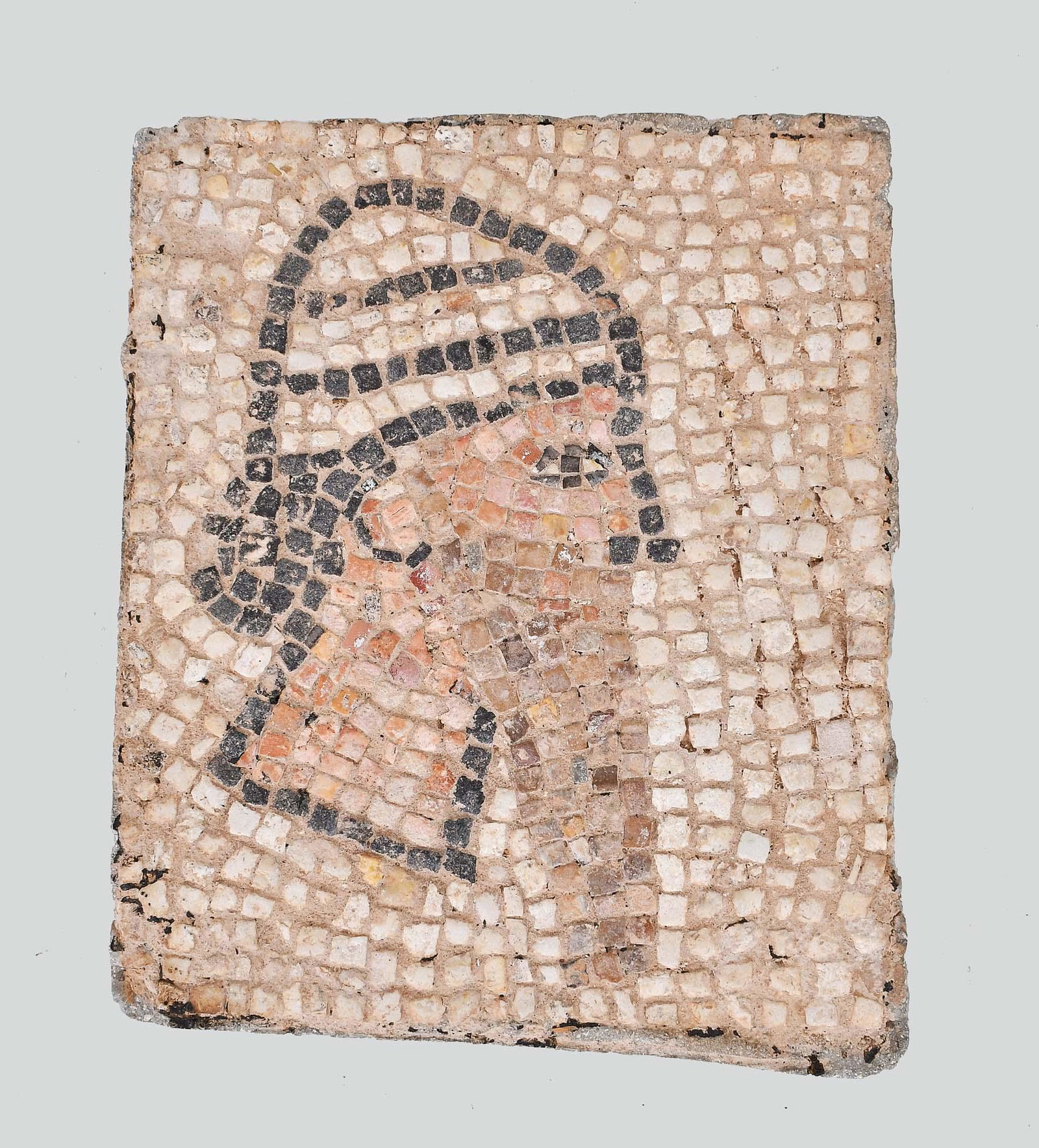LATE BRONZE AGE STONE MOSAIC OF A BEARDED MAN: The square panel with tiles forming the profile of a bearded man, wearing a cap. restored. . 12 in. by 10 in. (approx) Provenance: The Collection of Erwin and Sylvia Harvith, Detroit, MI, acquired in 
