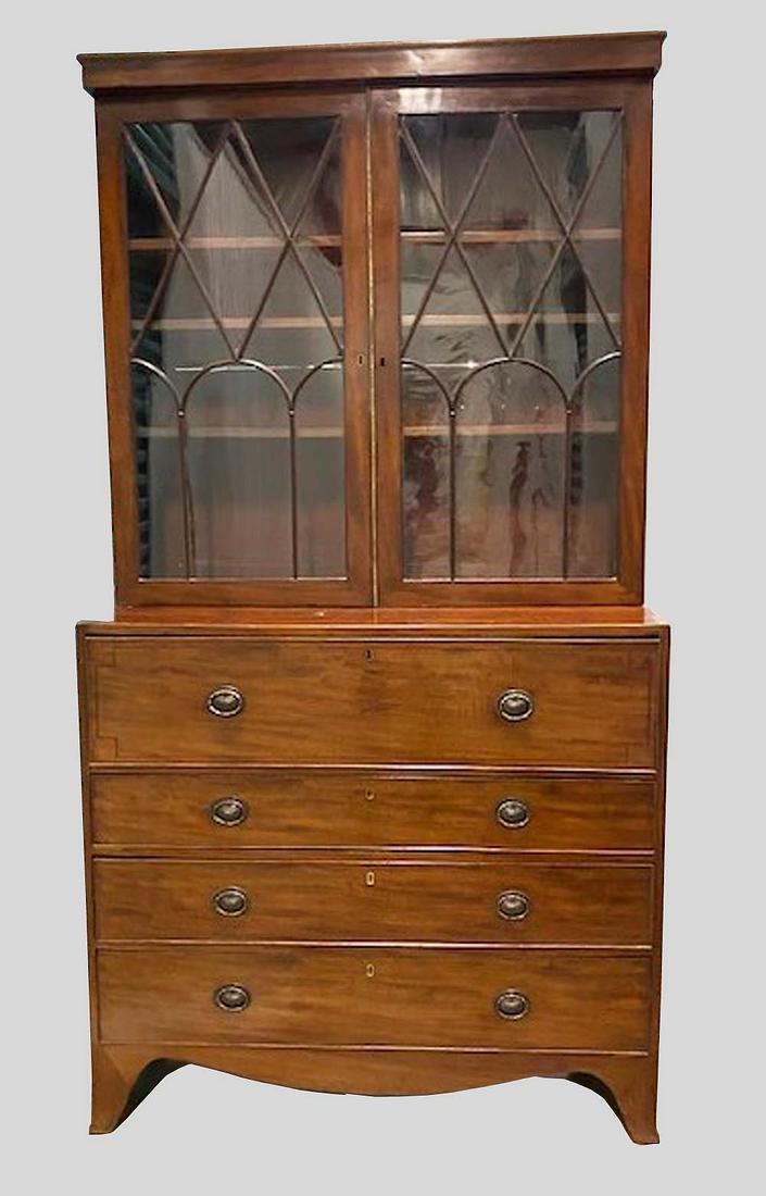 LATE GEORGE III MAHOGANY SECRETAIRE BOOKCASE: Circa 1810. In two parts, the upper with a flat cornice above a pair of glazed doors with carved mullions, opening to shelves, the lower part with a secretary drawer opening to a fitted interior, abov