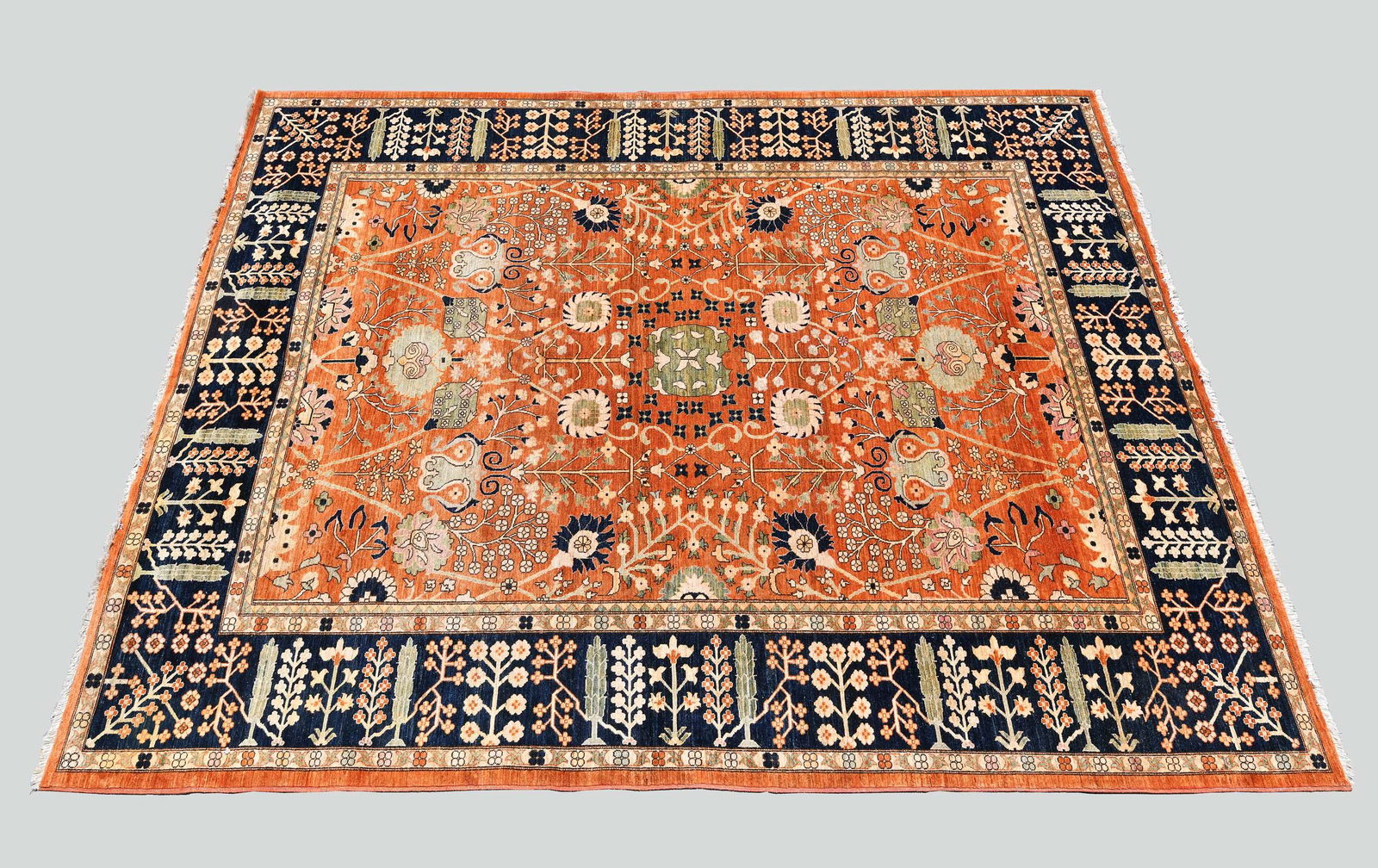 CONTEMPORARY HERIZ CARPET: The rust field with allover stylized foliage within a wide blue border with cypress trees and flowering stalks. Measuring 13 ft. by 10 ft. 2 in. (Cond: good)