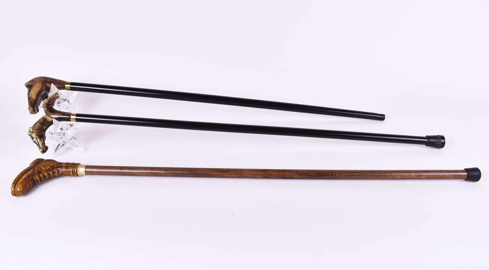 THREE ITALIAN WALKING STICKS: Modern. Two with horse head handles, one has glass-inset eyes, both on ebonized wood shafts; the third, with a handle depicting a boot, on a walnut shaft. Lengths 35 in. to 37 in. (Cond: good)