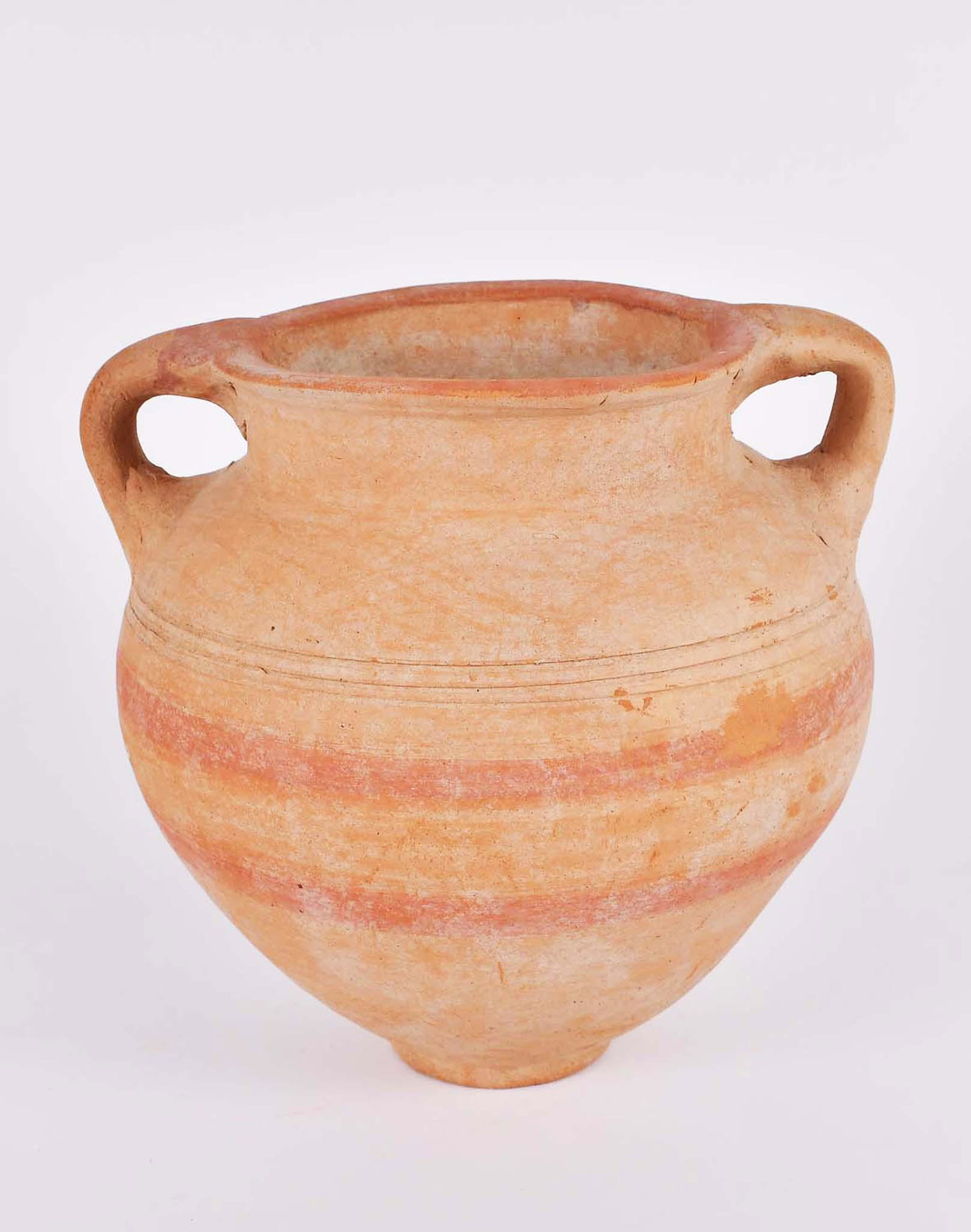 LATE BRONZE AGE CANAANITE RED TERRA COTTA AMPHORA: GAZA, B.C.E. 800. The tapered spherical body with a loop handle from rim to shoulder on each side, the mid body with two, now faded, wide red bands, beneath two incised horizontal lines, the exterior 