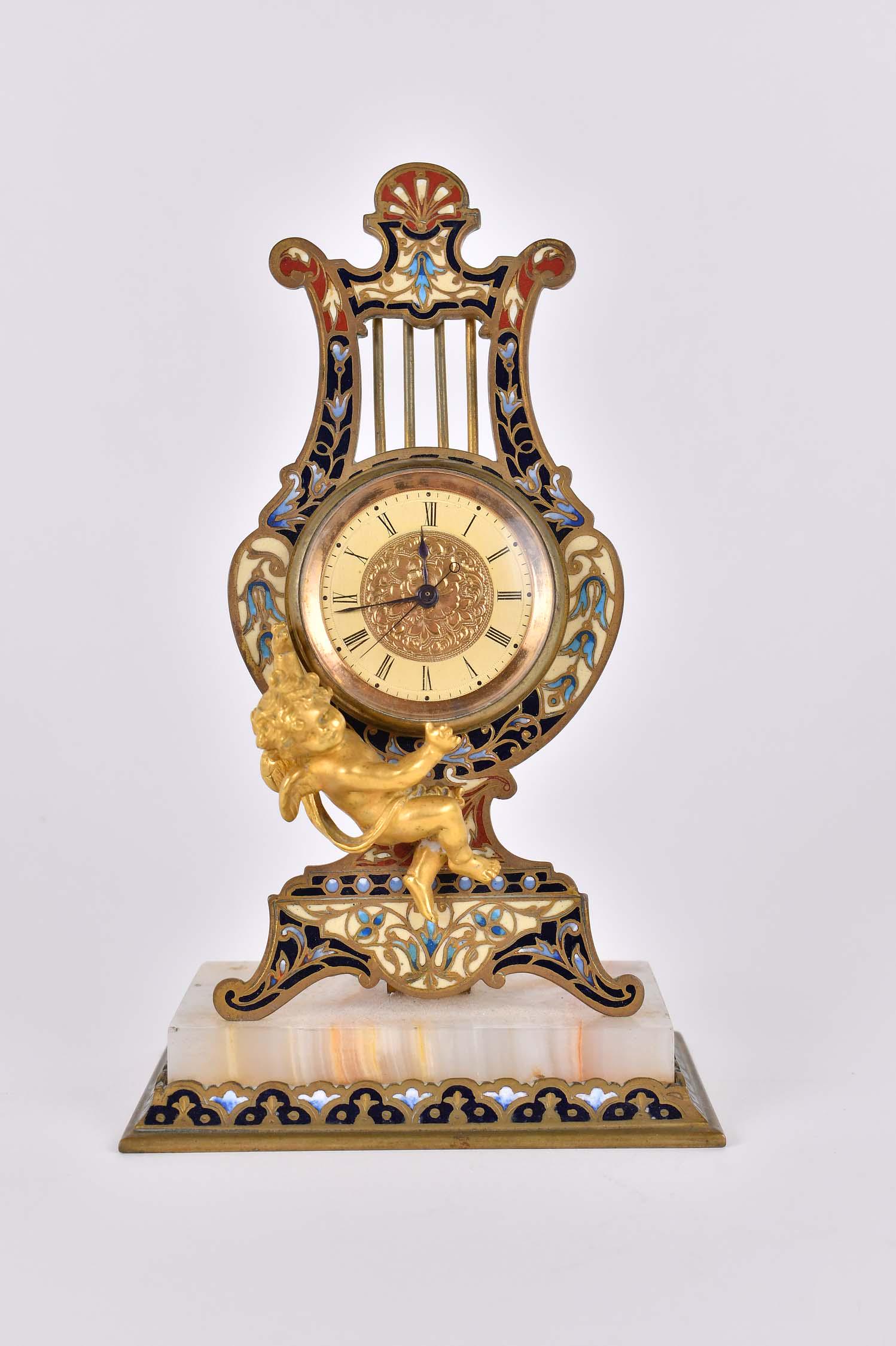 CHAMPLEVE ENAMEL & BRONZE LYRE-FORM TABLE CLOCK: French. Late 19th Century. Signed on the reverse Tiffany et Cie, Paris. The circular dial within an enamel inset lyre-form surround, fitted with a gilt bronze putto, on a conforming enamel inset and o