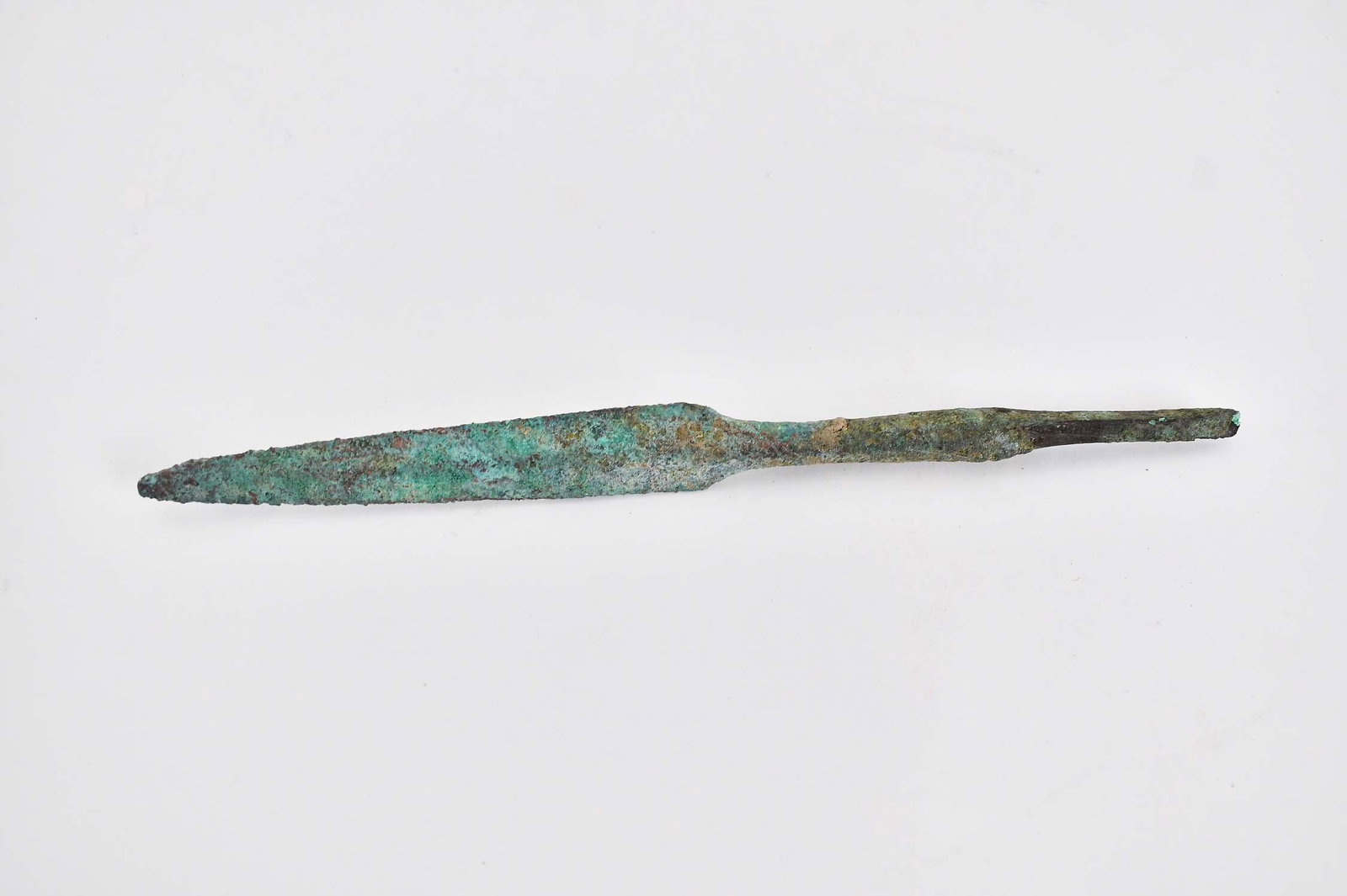 CANAANITE BRONZE SPEAR HEAD, 1800-1500 B.C.E.: The elongated blade tapering at one end to a point, the other to a rounded portion continuing to a shaped tang, with a green weathered patina. Length 8 in. Provenance: The Collection of Erwin and Sylv