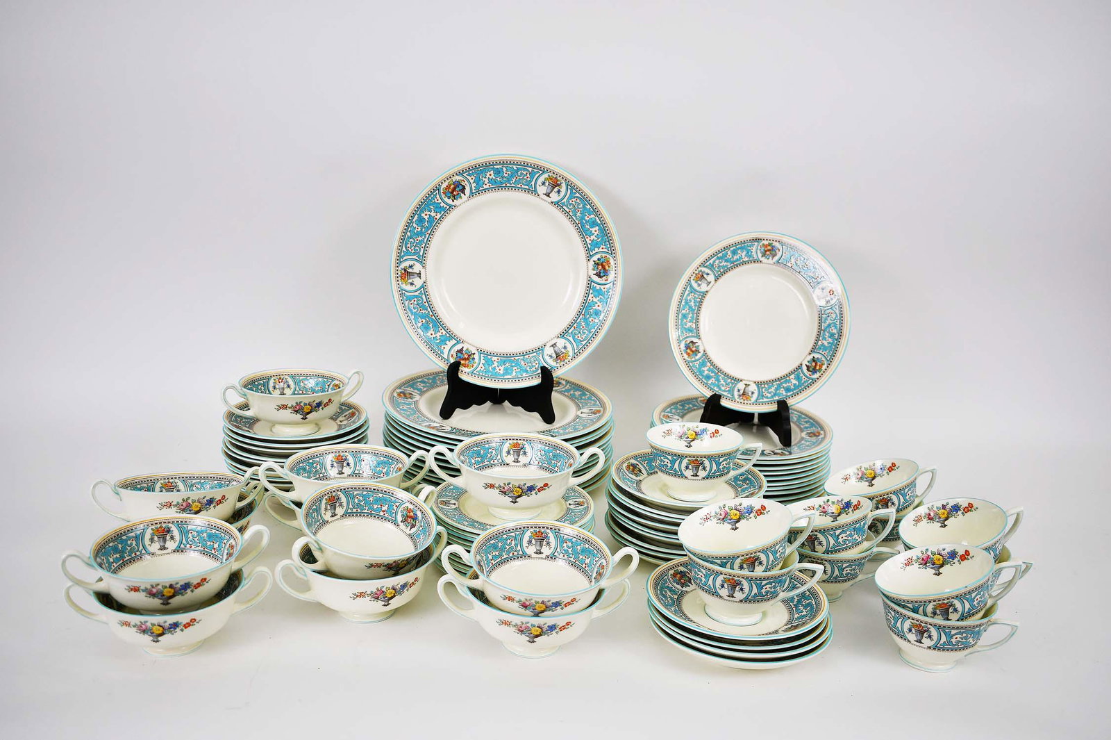 ROYAL DOULTON 82 PIECE EARTHENWARE DINNER SERVICE: Mid 20th Century. The underside of each marked. In the Somerset pattern. The rims with blue enameled scrolls dotted with reserves of flower-filled urns. Comprising: 12 dinner plates, 12 luncheon plate