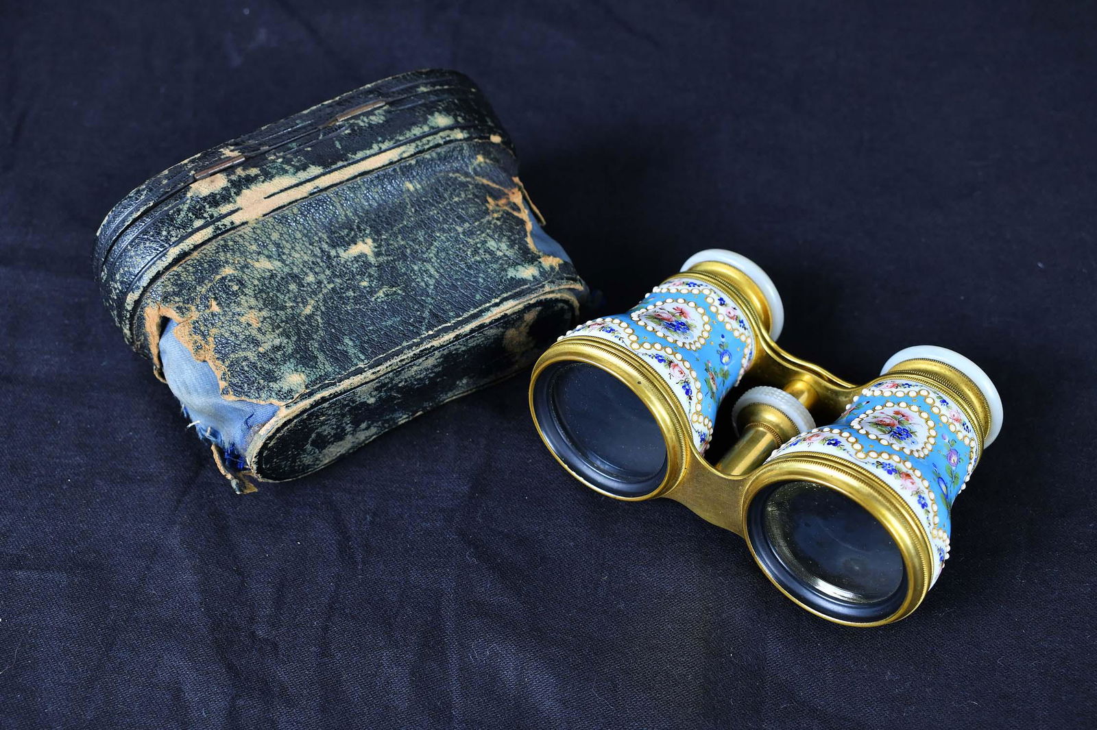 PAIR OF FRENCH ENAMEL DECORATED OPERA GLASSES: Lemarie Fabt., Paris. 1860 to 1880. With mother of pearl eye cups, decorated with flowers on a light blue ground, with a black leather case, distressed. (Cond: glasses are good, no chips to enamel)