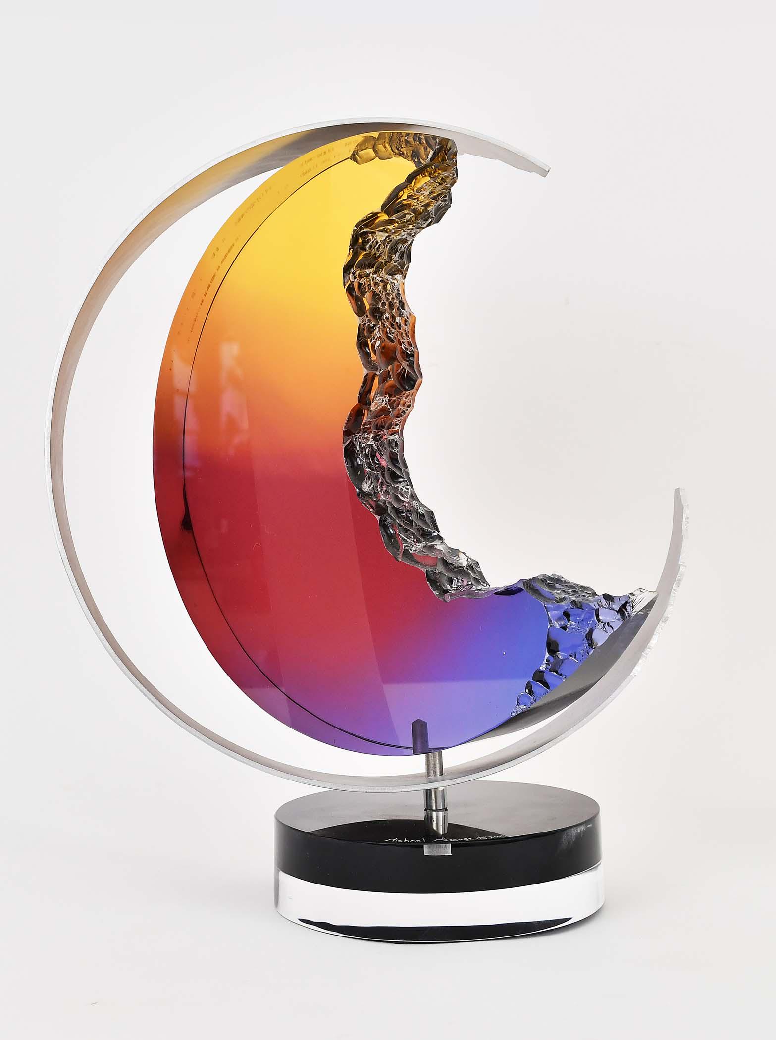 MICHAEL GEORGE (American. 20th Century): Moonstruck, 2004. Signed, dated on the base. Kinetic Studio Sculpture of an amber-colored acrylic crescent moon with inside jagged edge, with an outer aluminum circular band, on a circular base. The o