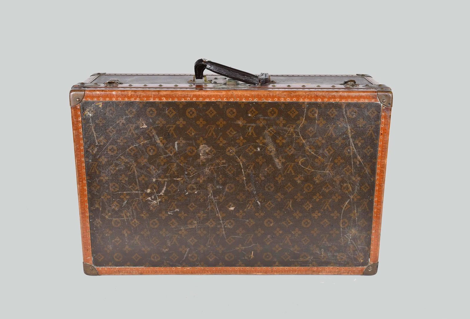 VINTAGE LOUIS VUITTON MONOGRAMMED CANVAS HARD CASE: The latches and lock plate inscribed LV and Louis Vuitton, the interior with Louis Vuitton gold paper label, numbered 793530. Rectangular with patinated brass/copper lock plate, clasps, and corner mou