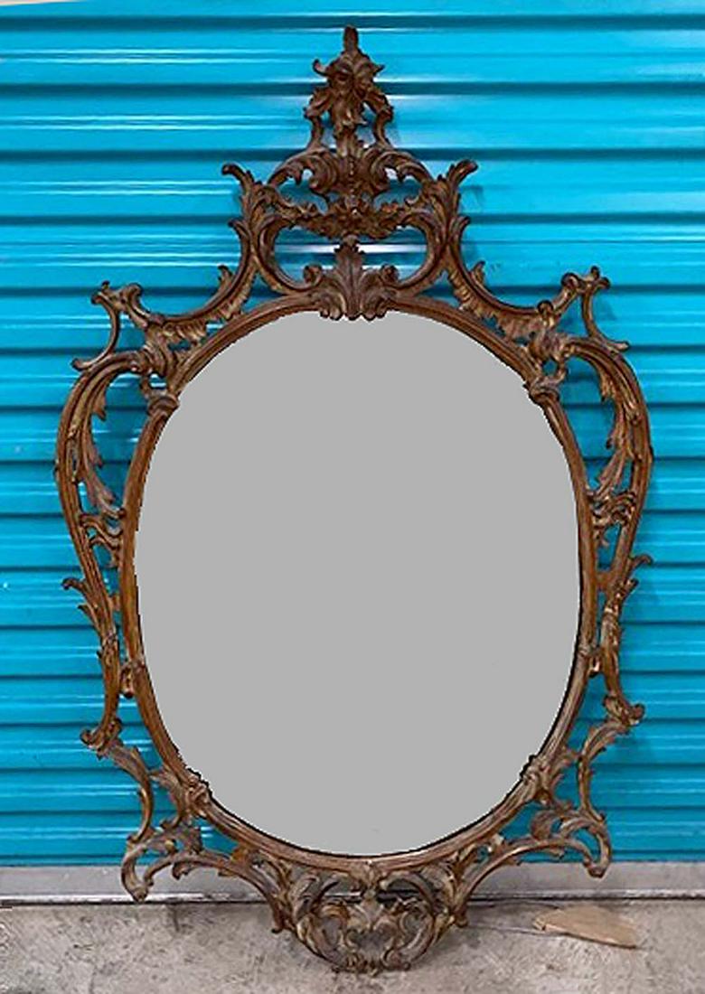 ROCOCO STYLE CARVED WOOD MIRROR: English or German, circa 1860. The oval mirror plate within a surround, with cresting of C-scrolls and leafage. Height 5 ft. (approx)