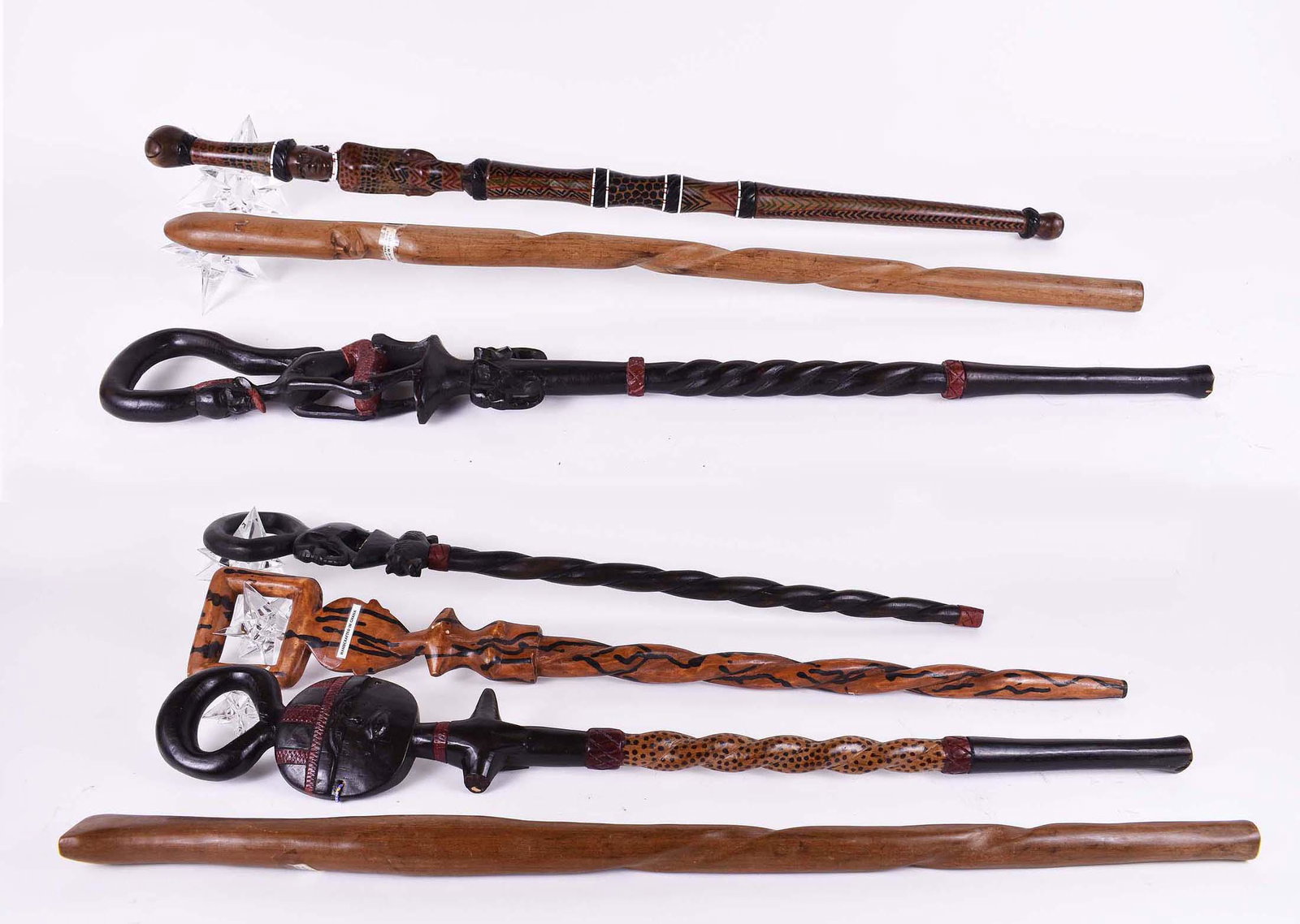 SEVEN VARIOUS WOOD AFRICAN WALKING STICKS: Mainly from Kenya and Ghana. Modern. Including, two ebonized or part ebonized carved with an elephant or the face of a full moon, another painted and carved with a female figure, two simplly carved st