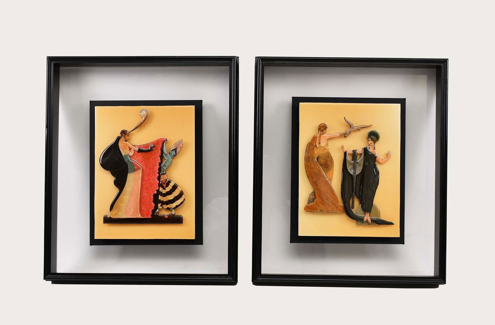 MANNER OF ERTE, TWO ACRYLIC RELIEFS: Pair of molded colored acrylic panels, with raised theatrical figures, set in an ebonized frame. Measuring 12.25 by 9.5 in., overall 20.5 by 17 in. (Cond: one panel askew from frame, otherwise good)