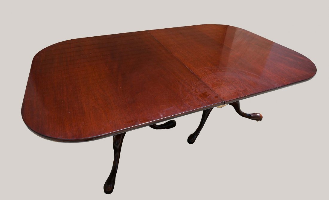 GEORGE III STYLE MAHOGANY 2-PEDESTAL DINING TABLE: Modern, made by William Tillman. The rectangular top with rounded corners, opening to accommodate two leaves, above two ring-turned pedestals on three scrolled legs, ending in pad feet, on casters. He