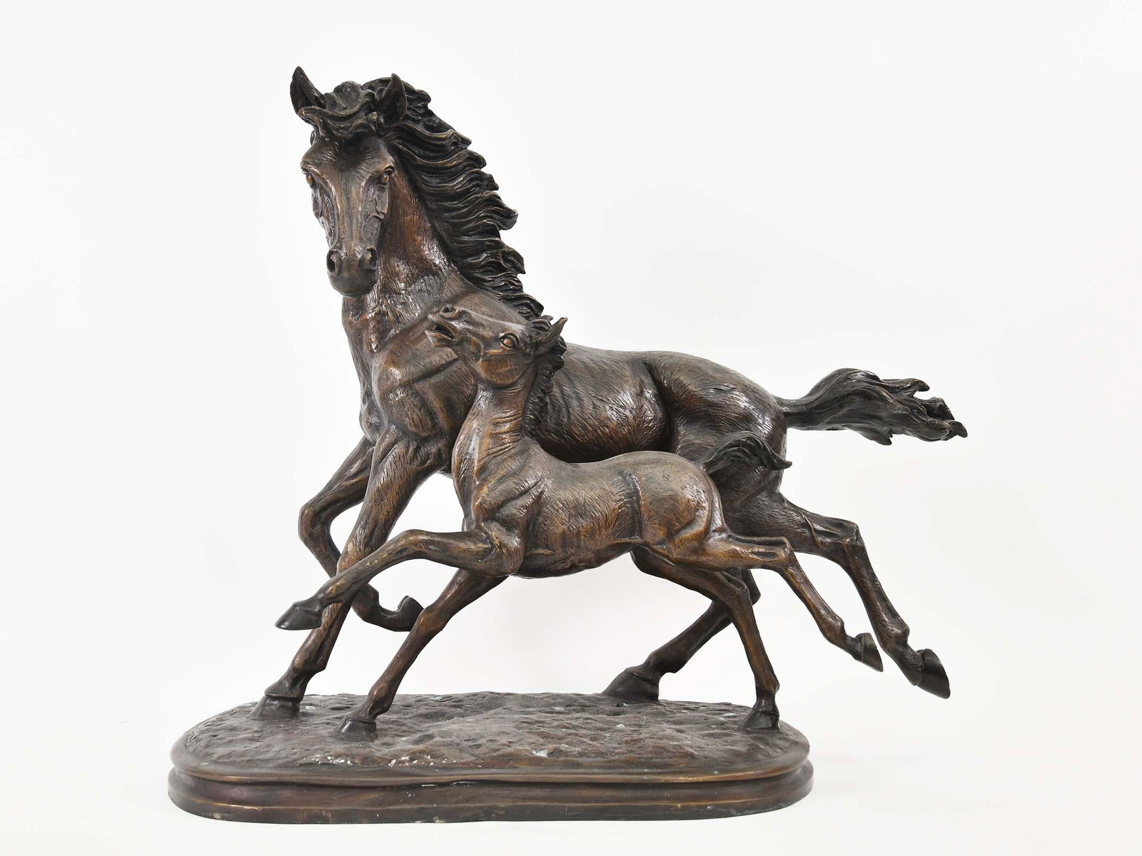 PATINATED BRONZE OF A MARE AND HER FOAL: Realistically modeled, running side by side, on an oval base, with a gold toned brown patina. Height 21.5 in. Width 25 in.