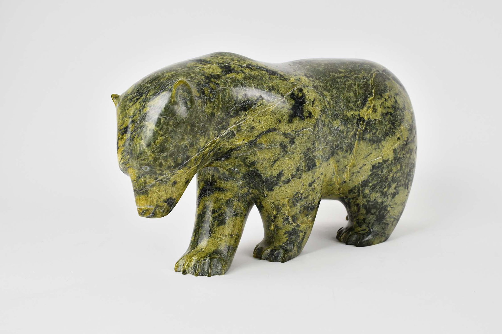 LARGE INUIT CARVED GREEN MARBLE POLAR BEAR: Signed on the underside of a foot indistinctly and dated 1995. The spinach green marble with a pleasing natural mottled and striated overall pattern. Height 7.5 in. Width 14 in. Depth 5 in. (Cond: goo