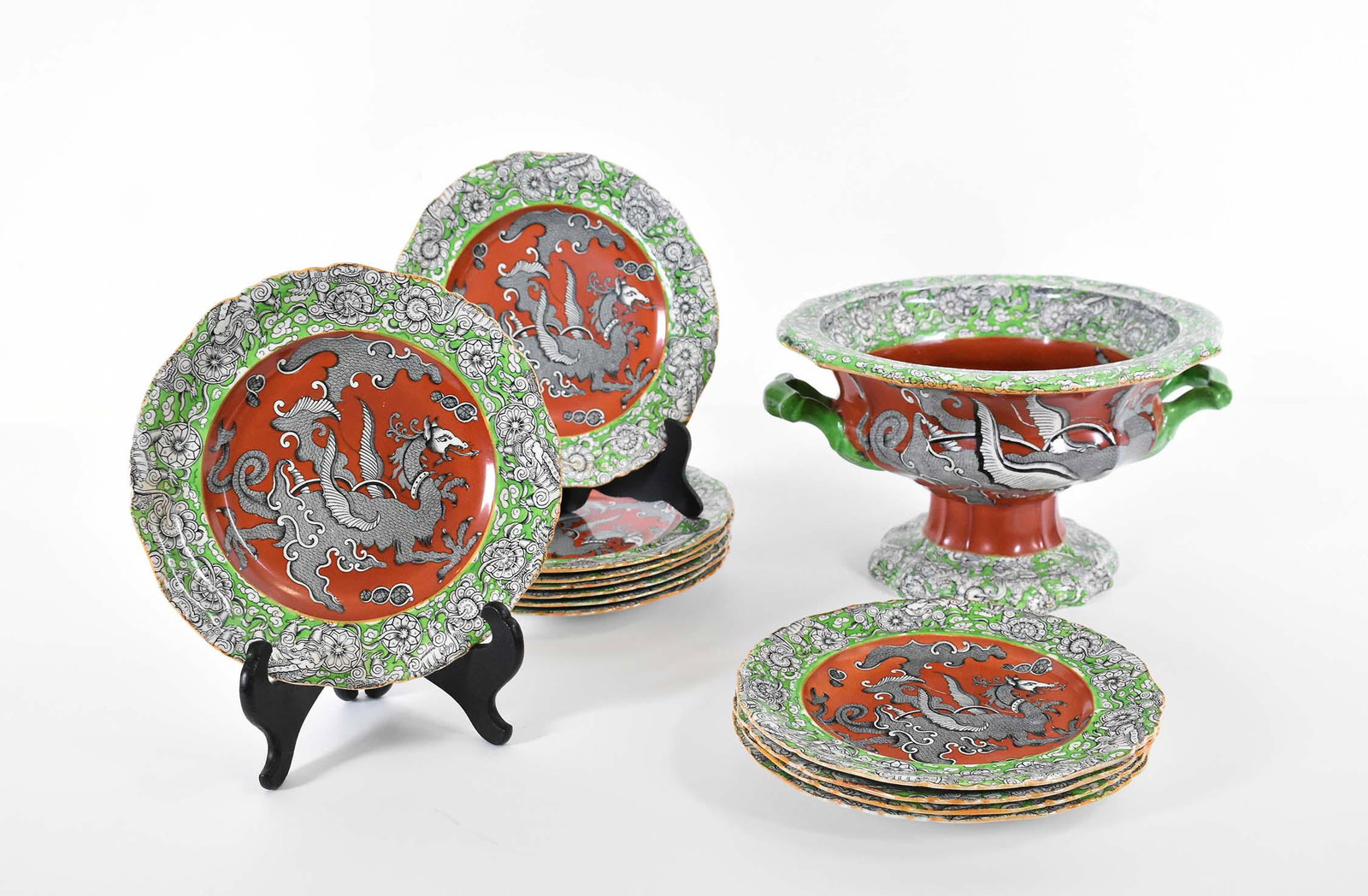 TWELVE MASONS IRONSTONE PLATES & CENTER BOWL: Marked Masons Ironstone, impressed logo and numerals in red. The center recesses decorated with a dragon on an iron red ground, with green borders, the footed bowl decorated en suite, and with a handl